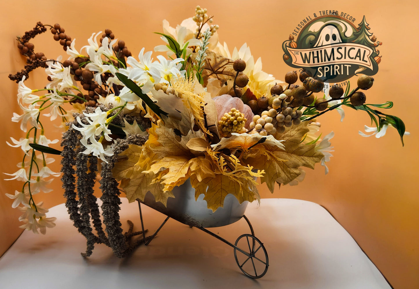 Decorative flower arrangement in a vintage-style wheelbarrow with 'Whimsical Spirit' branding.