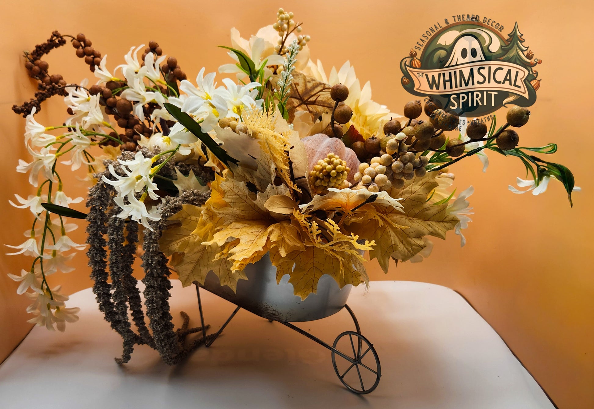 Decorative flower arrangement in a vintage-style wheelbarrow with 'Whimsical Spirit' branding.