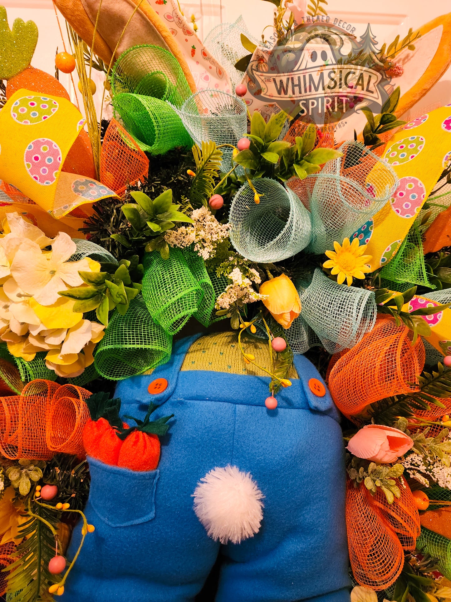 Decorative wreath with blue character, colorful mesh, and 'Whimsical Spirit' sign.