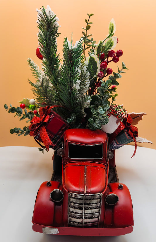 Decorative red truck with Christmas tree and ornaments on a white surface