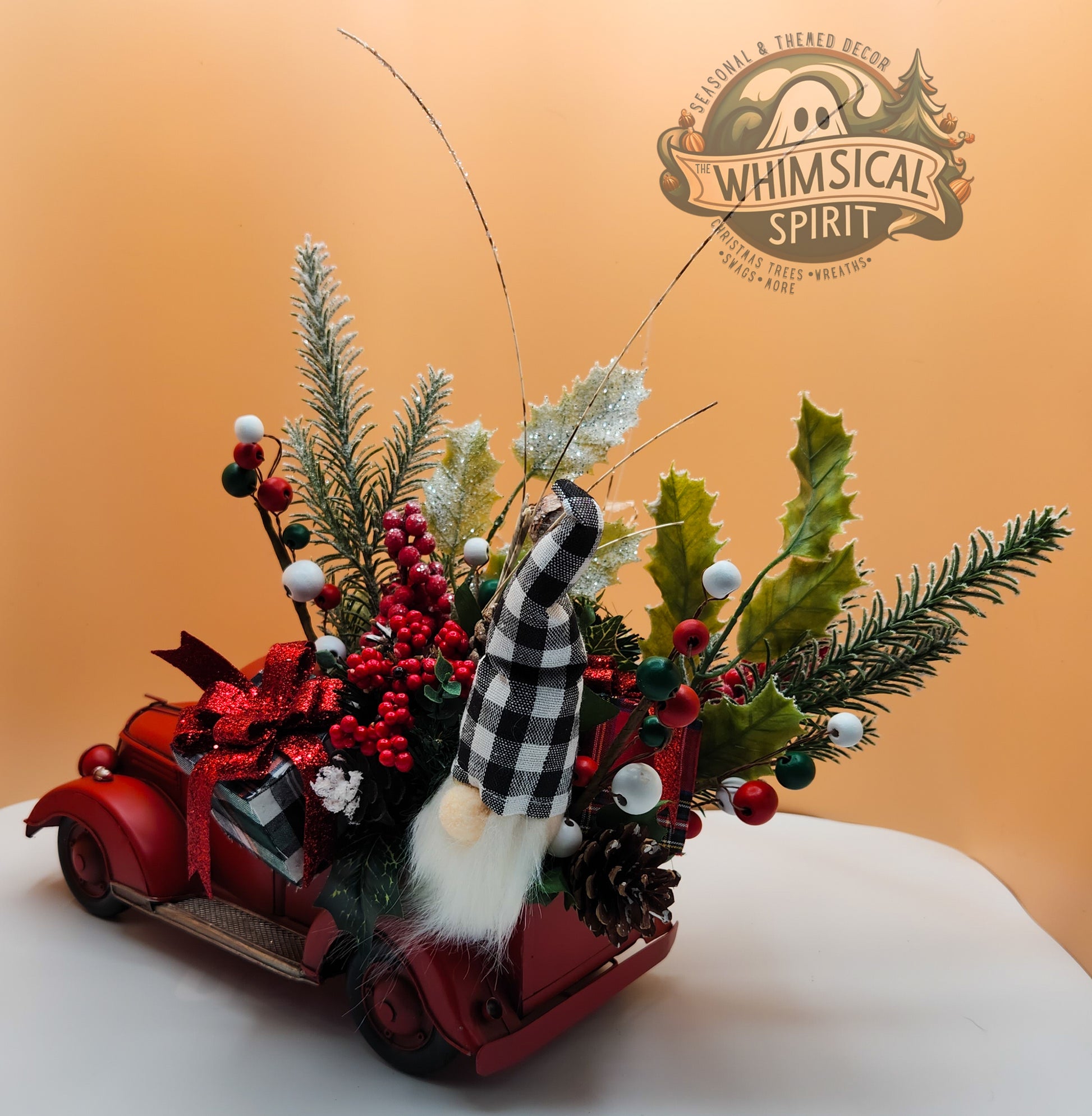 Christmas decorative display with red car, checkered gnome, festive greenery on orange background, The Whimsical Spirit branding