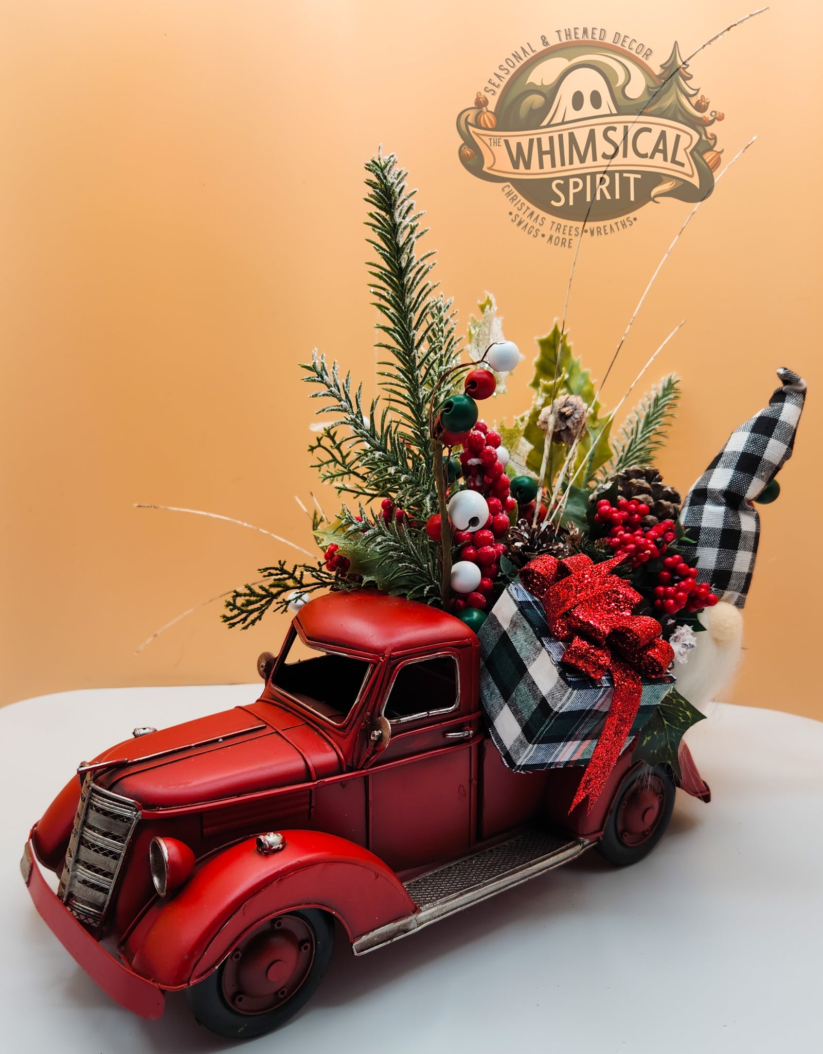 Festive red truck with holiday decorations and plants on beige background, featuring Whimsical Spirit logo, Christmas theme.