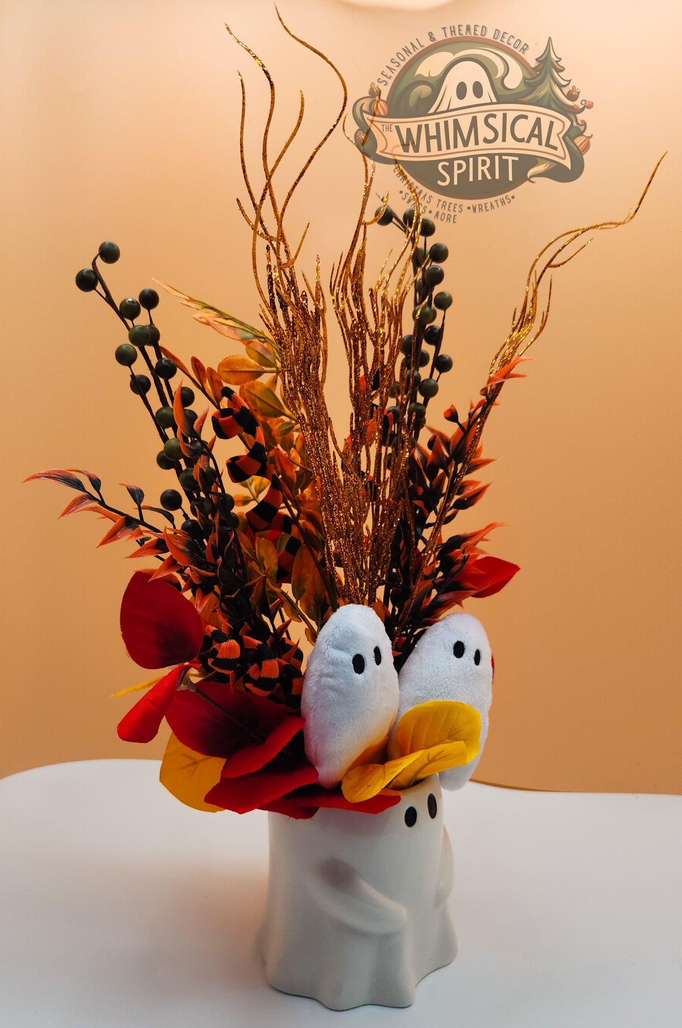Decorative arrangement with ghost-themed vase against a plain background