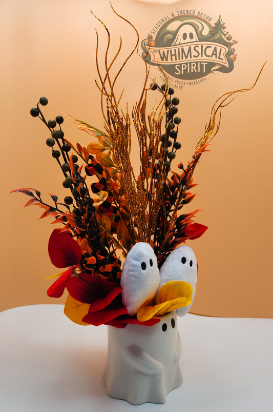 Decorative arrangement with ghost-themed vase against a plain background