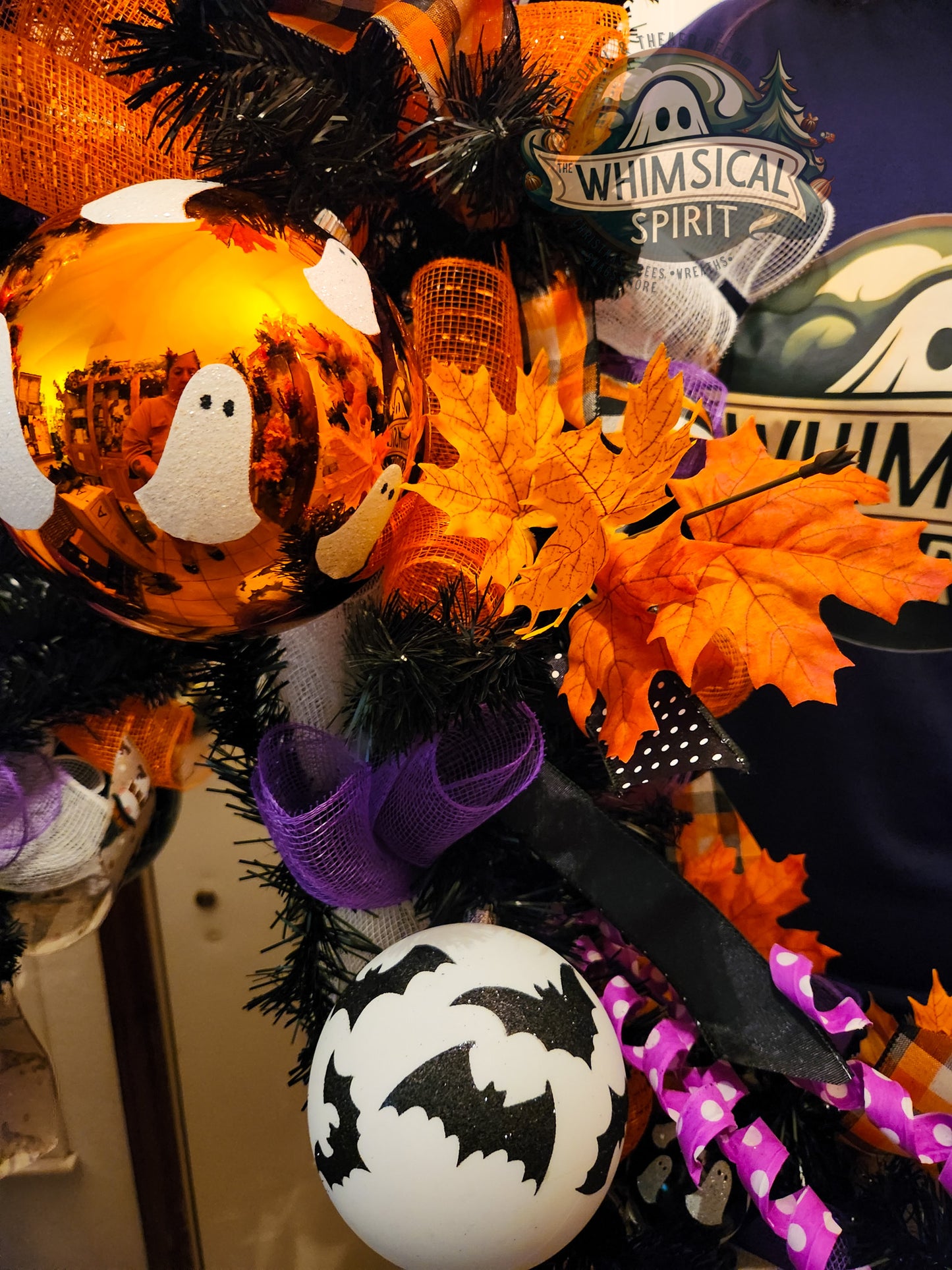 Halloween-themed wreath with pumpkins, ghosts, and bats on a door.