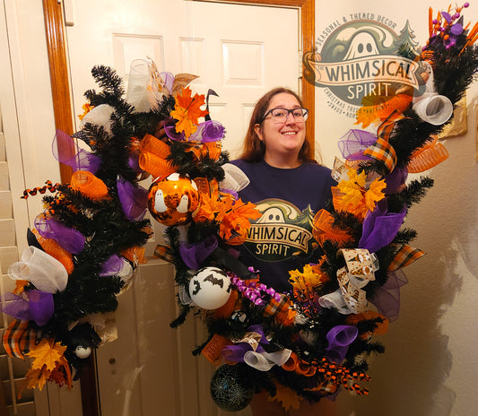 Person standing behind a Halloween-themed wreath with 'Whimsical Spirit' branding.