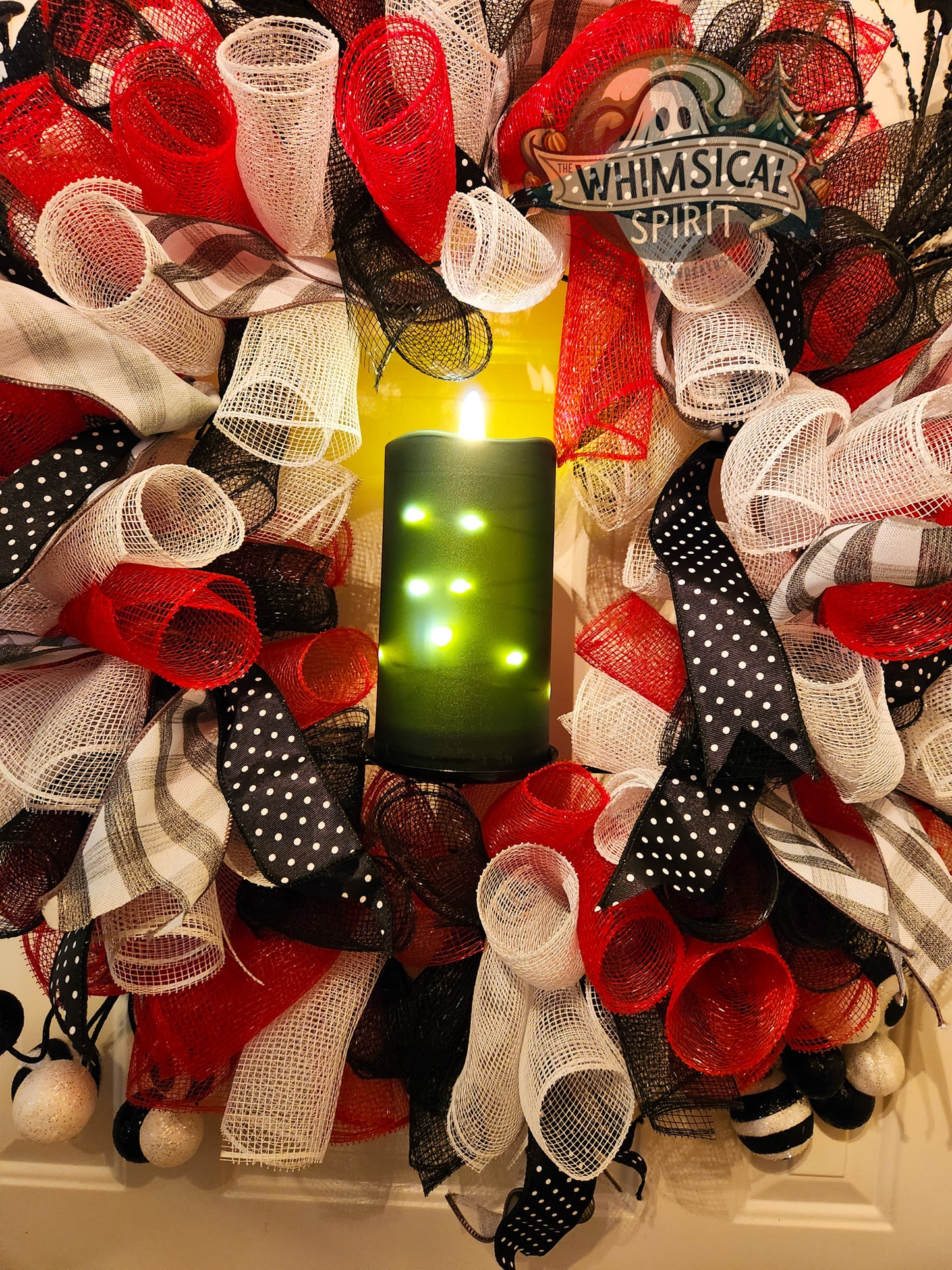 Decorative wreath with ribbons and a candle, featuring the brand 'Whimsical Spirit'.