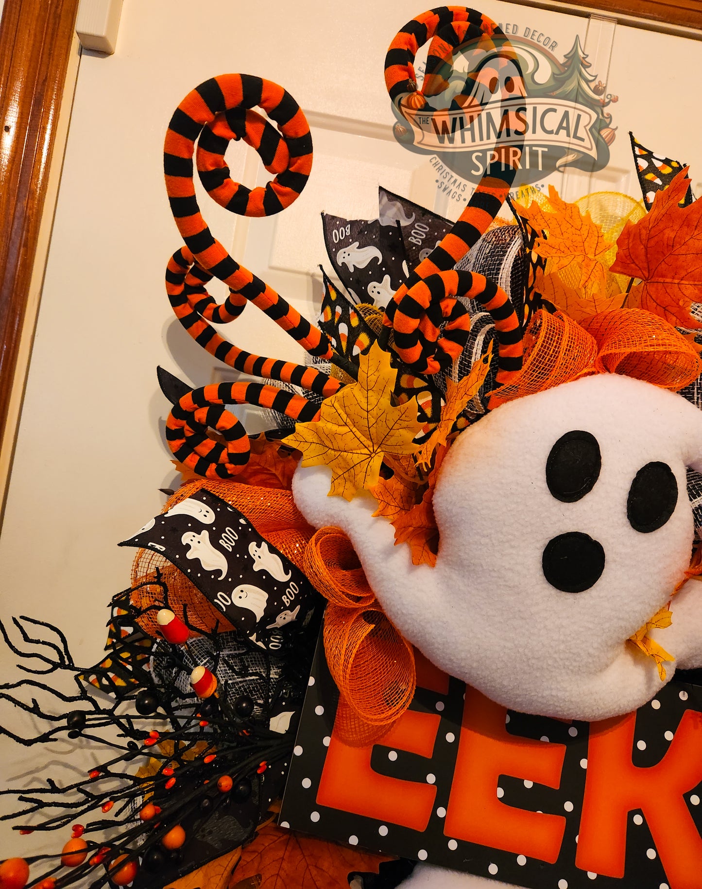 Halloween-themed wreath with ghost, snake, and decorative elements on a plain background