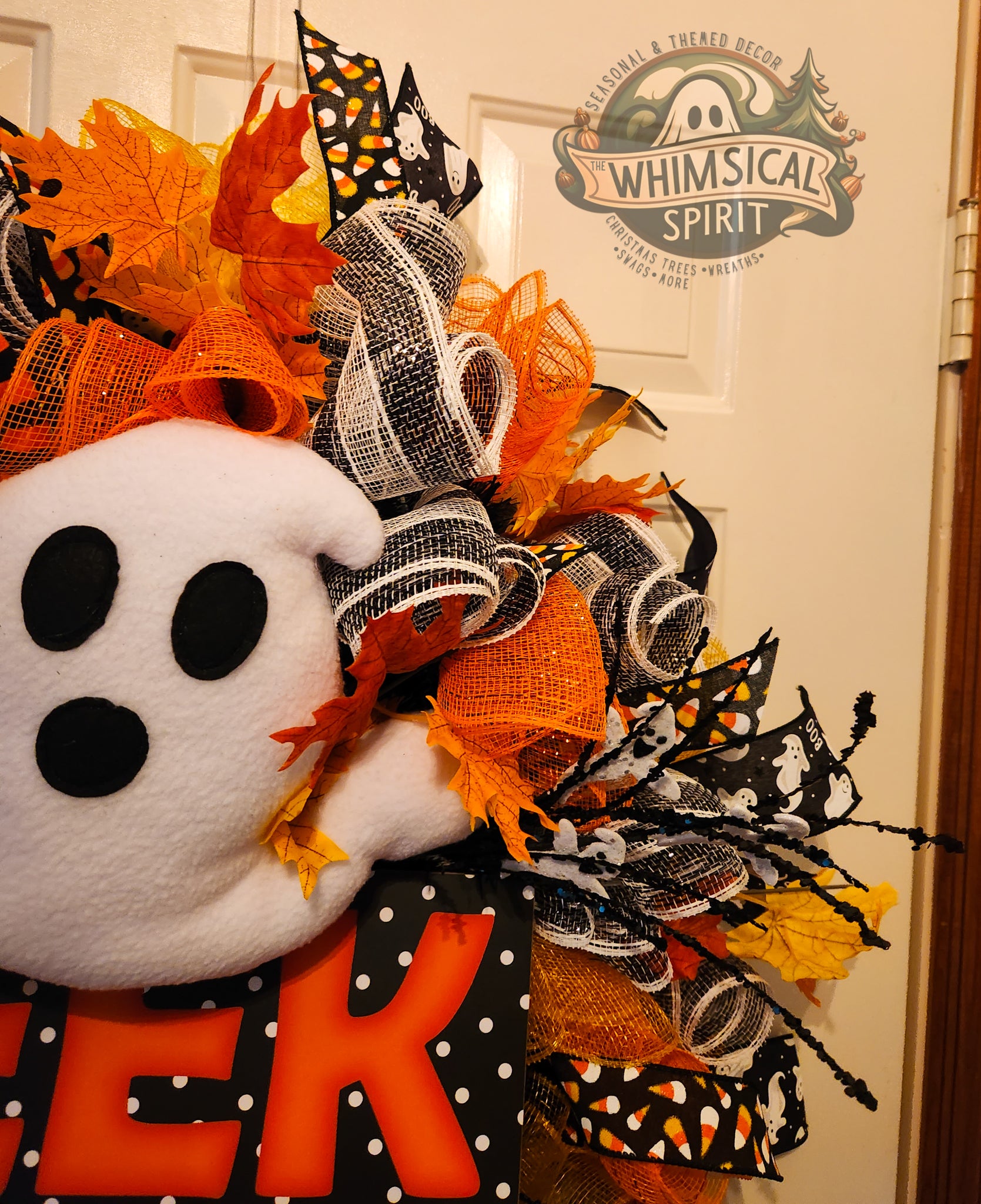 Halloween-themed wreath with ghost, candy corn, and witch hat on a door with 'Whimsical Spirit' branding.