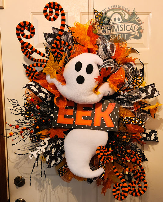 Halloween wreath with ghost and 'Eek!' sign on a door, featuring orange, black, and white colors.