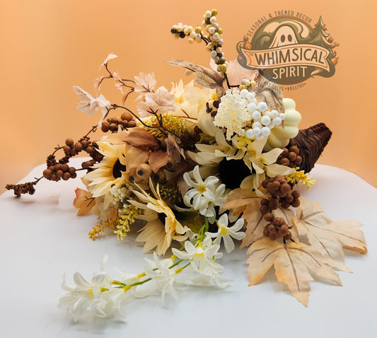 Rustic Grace cornucopia with cream florals, natural foliage, and earthy accents in a woven horn, blending neutral elegance with seasonal charm
