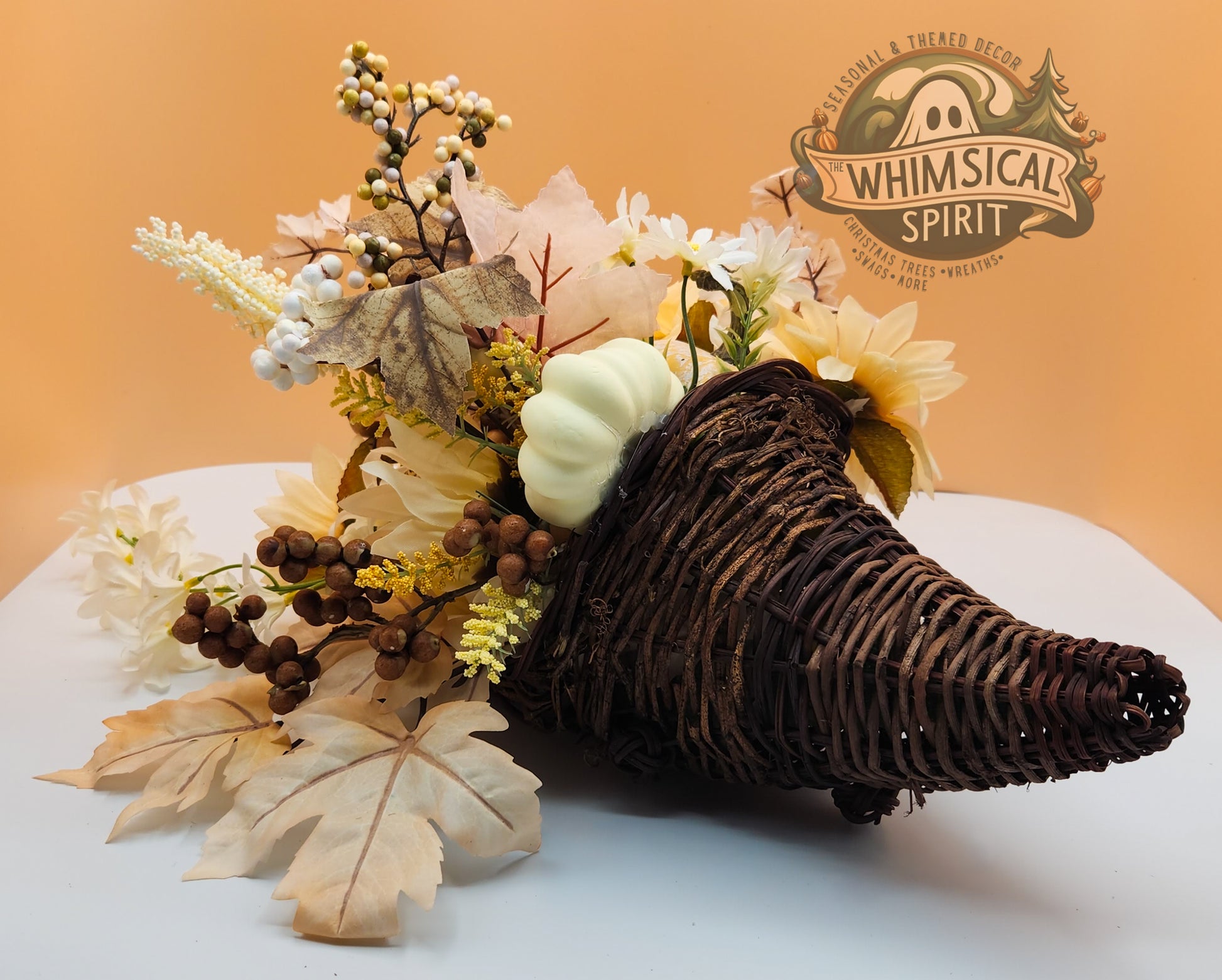 Rustic Grace decorative cornucopia with cream flowers, leaves, berries, and greenery on a white surface, with Whimsical Spirit branding