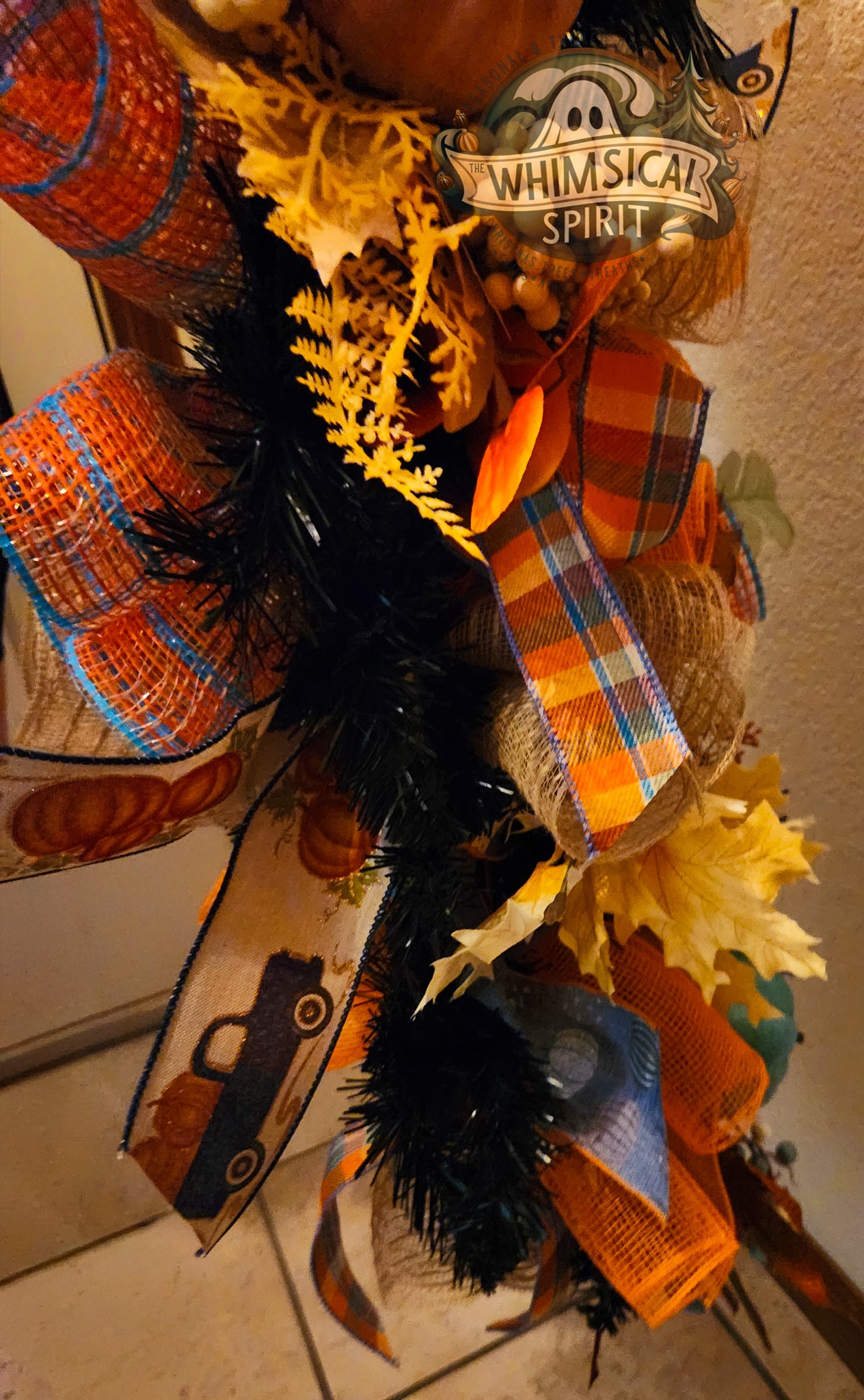 Decorative Autumn wreath with ribbons, feathers, and pumpkins on a neutral background