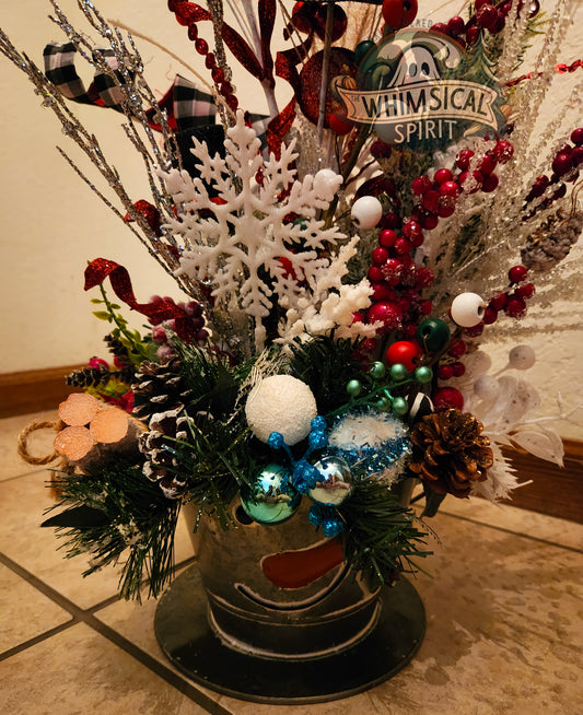 Decorative Christmas arrangement with ornaments and a 'Whimsical Spirit' sign in the background.