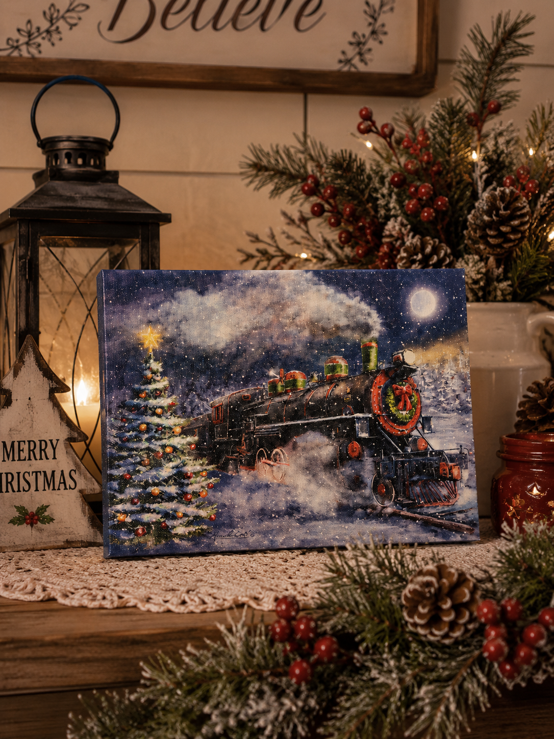 Christmas train light-up tabletop canvas styled with pine greenery, red berries, lantern, pinecones, and cozy holiday decor.