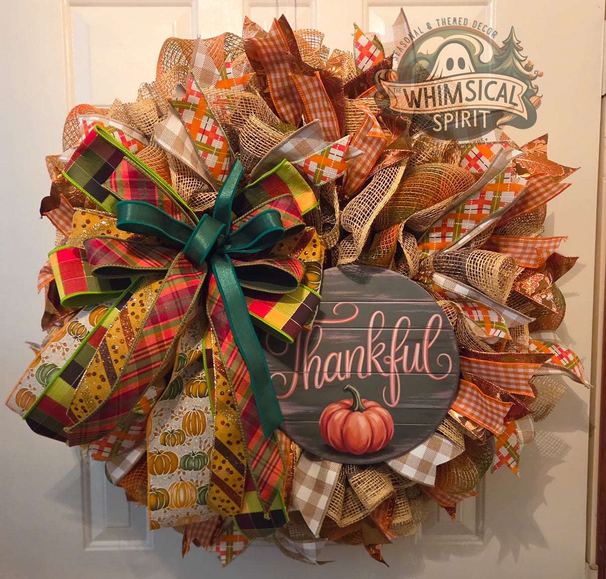 A Tartan Thanksgiving mesh wreath with a Thankful pumpkin sign, layered fall ribbons, and an oversized plaid bow.