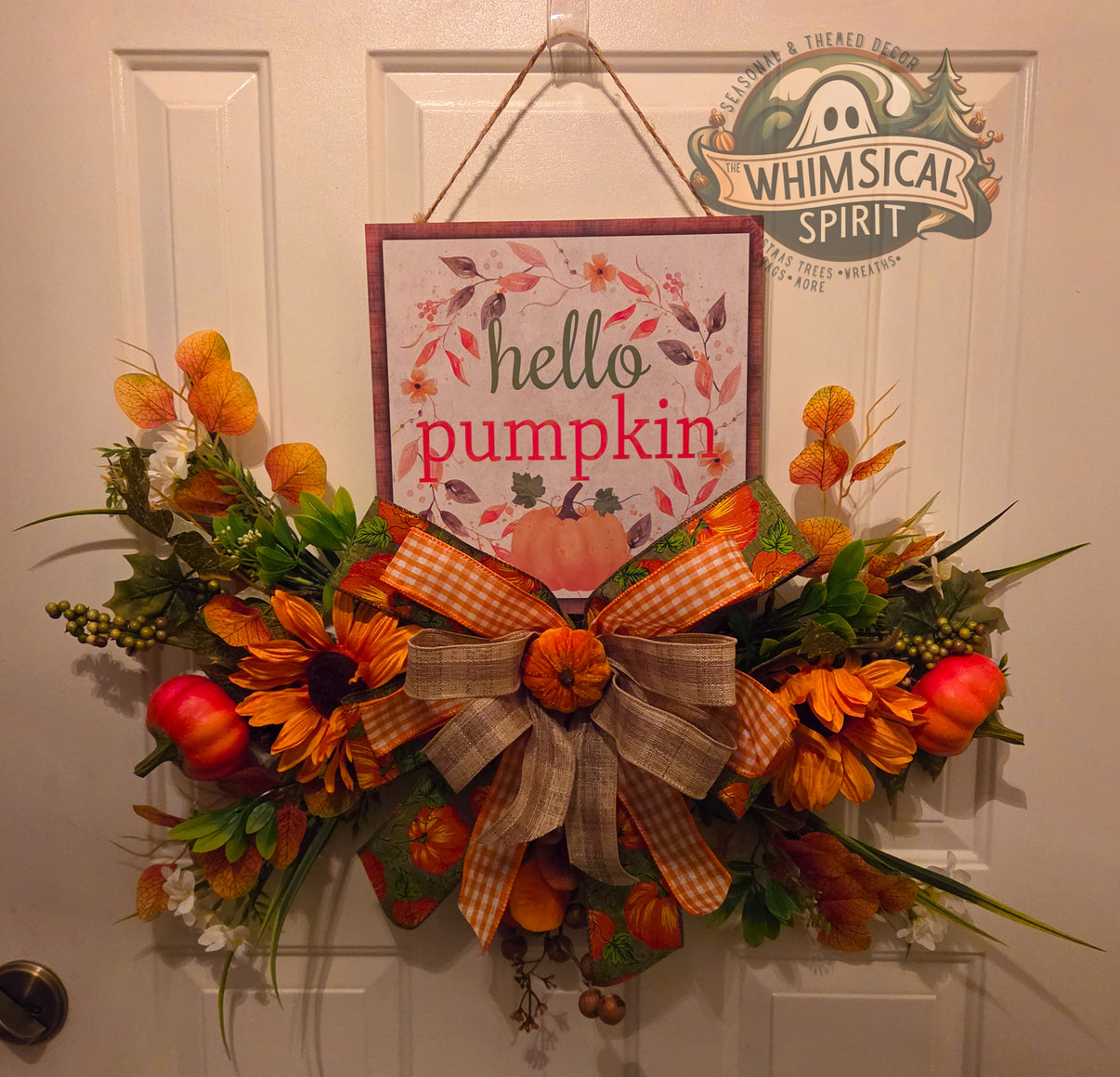 Fall pumpkin floral door hanger with Hello Pumpkin sign, orange flowers, pumpkin accents, and layered fall bow.