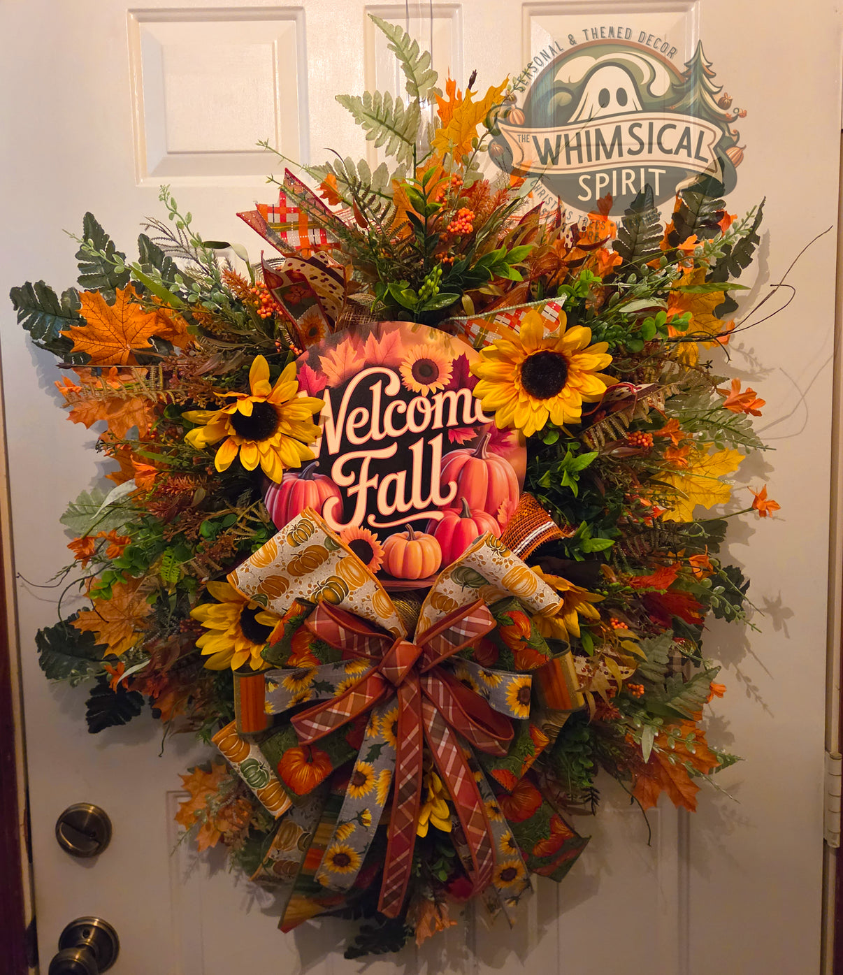 Oversized fall wreath with a Welcome Fall sign, pink pumpkins, yellow sunflowers, autumn foliage, greenery, and layered seasonal ribbons.