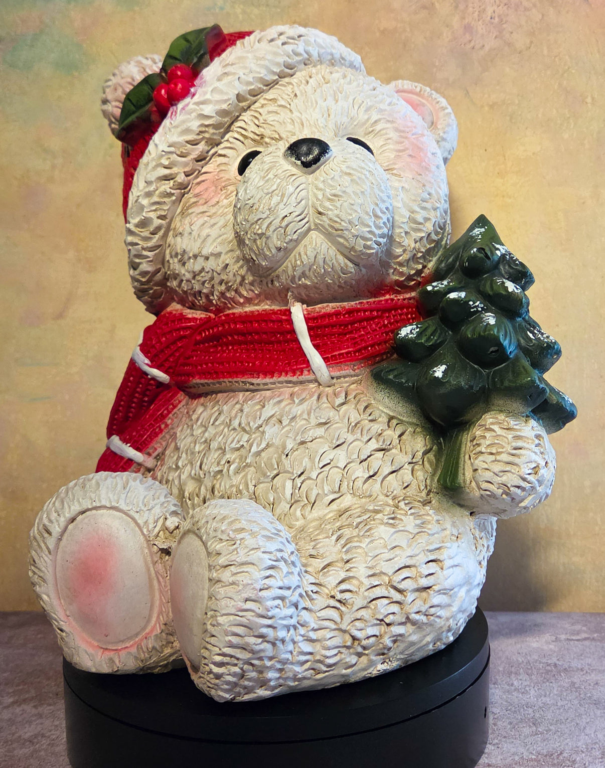 Baxter the Christmas Bear large resin polar bear figurine with red scarf, Santa hat, holly accents, and green Christmas tree.
