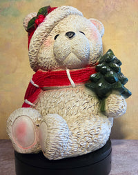 Baxter the Christmas Bear large resin polar bear figurine with red scarf, Santa hat, holly accents, and green Christmas tree.