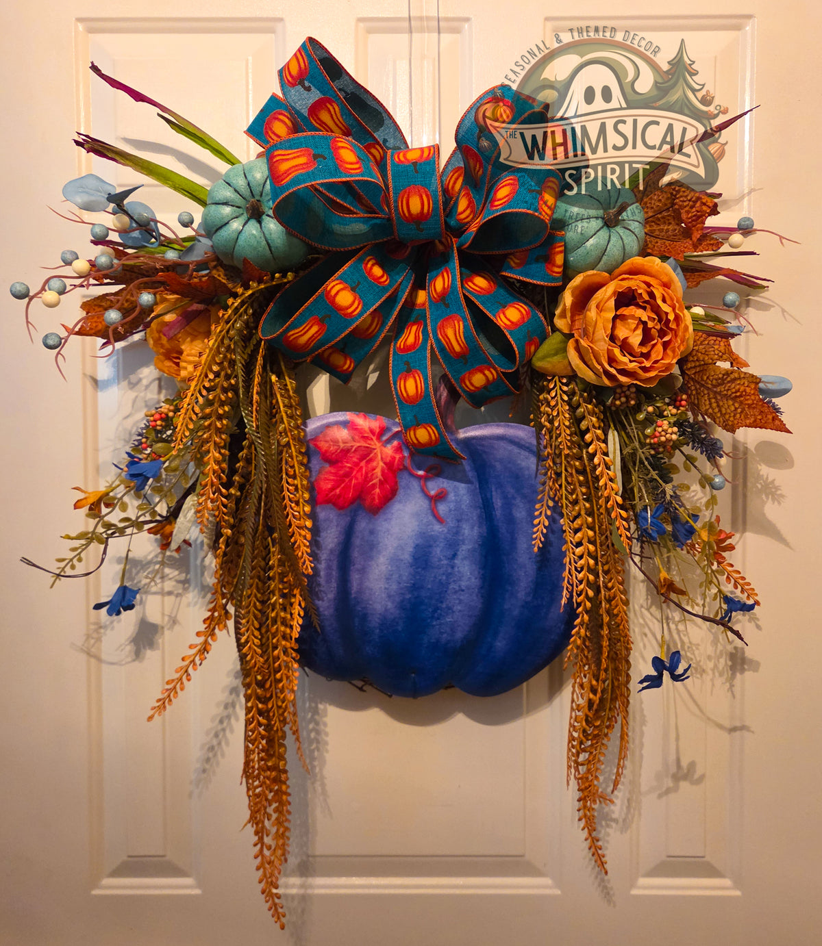 Blue pumpkin fall grapevine wreath with teal pumpkin-print bow, florals, berries, and cascading amber foliage.