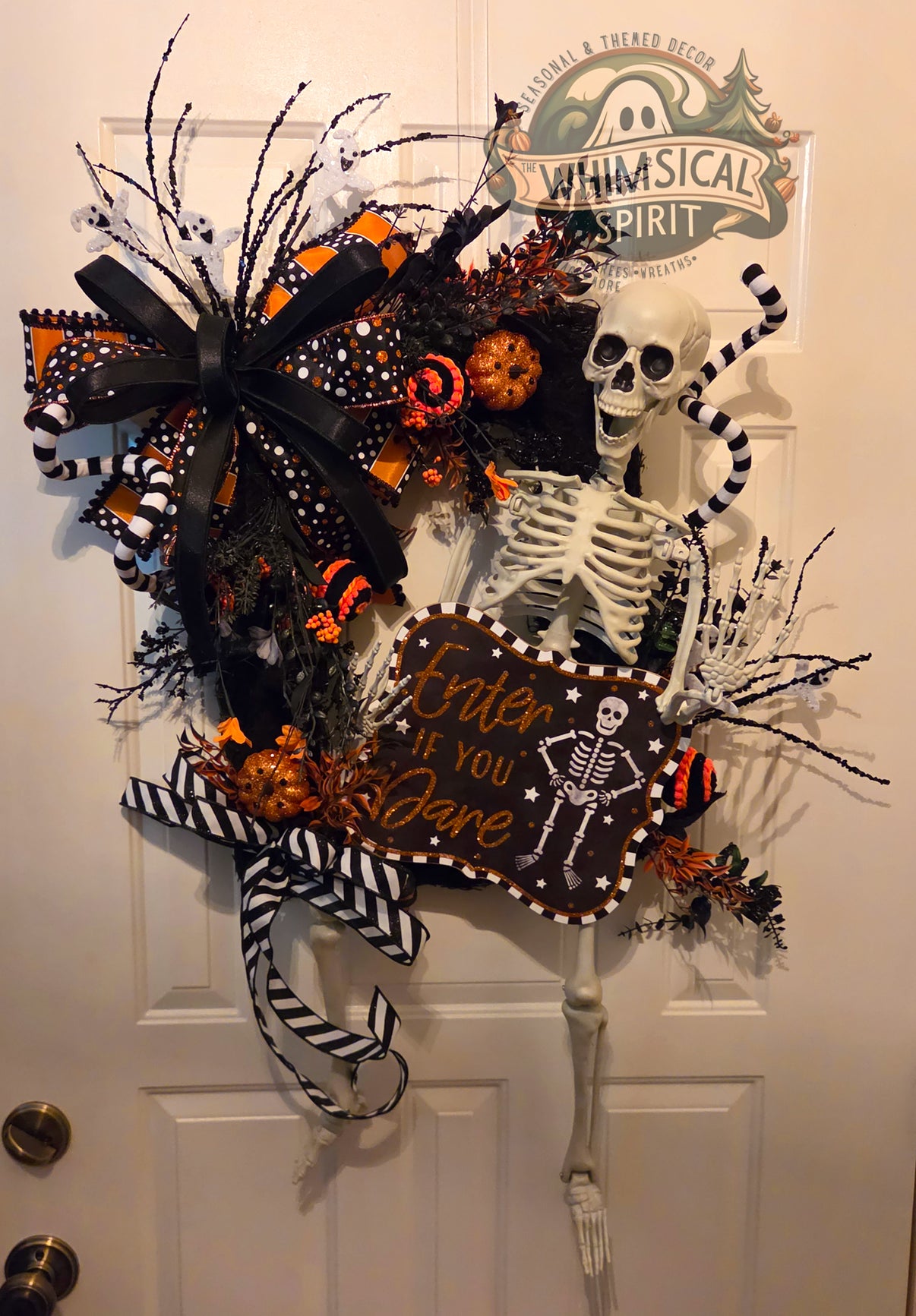 Oversized skeleton Halloween wreath with an Enter If You Dare sign, black-and-orange ribbons, striped accents, pumpkins, and dark foliage.