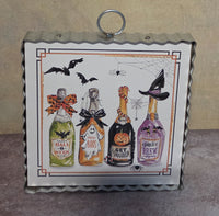 Bottled Boos framed Halloween metal art featuring four decorated potion bottles, flying bats, spiders, webs, and playful spooky labels.