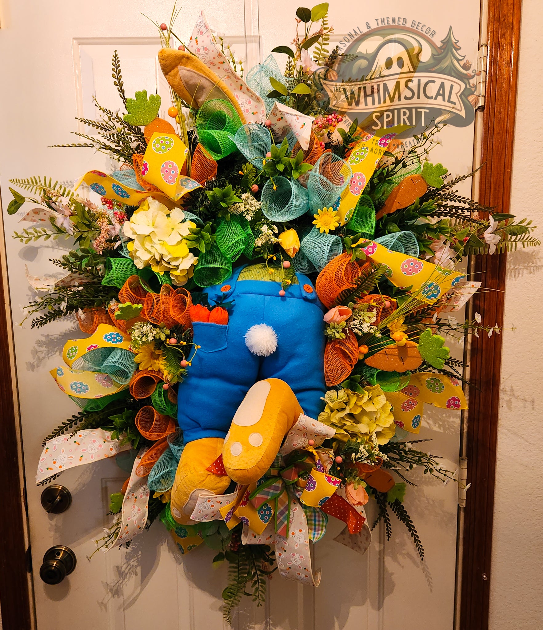 Colorful wreath with cartoon character design on a door, featuring the brand 'Whimsical Spirit'.