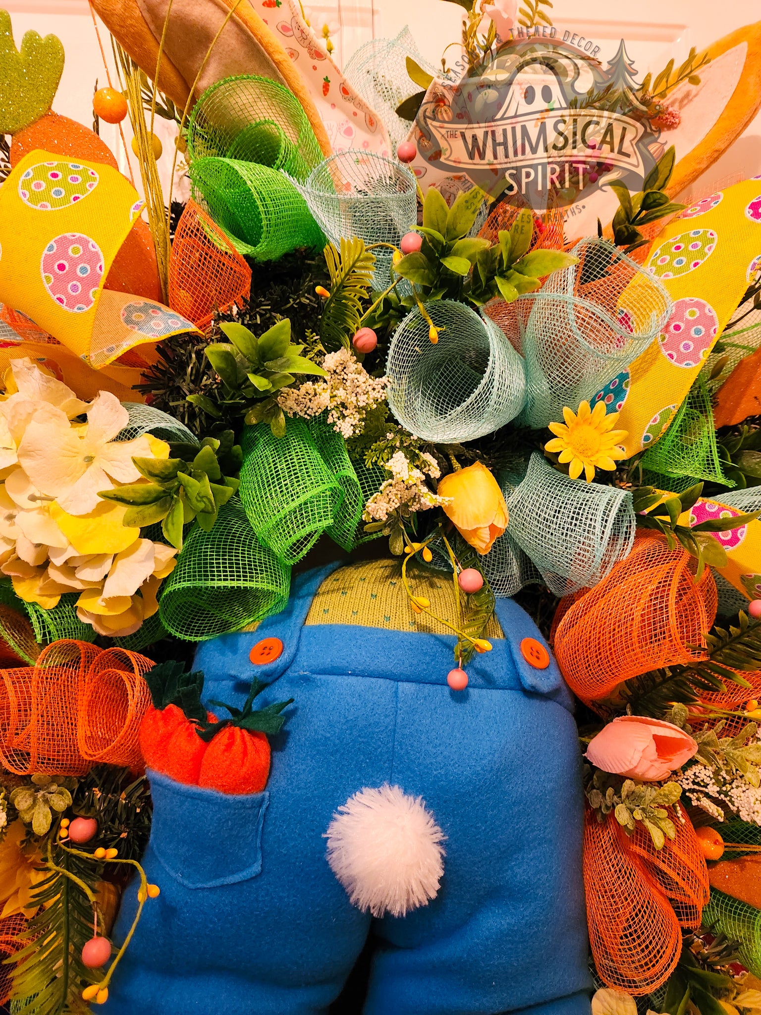 Decorative wreath with blue character, colorful mesh, and 'Whimsical Spirit' sign.