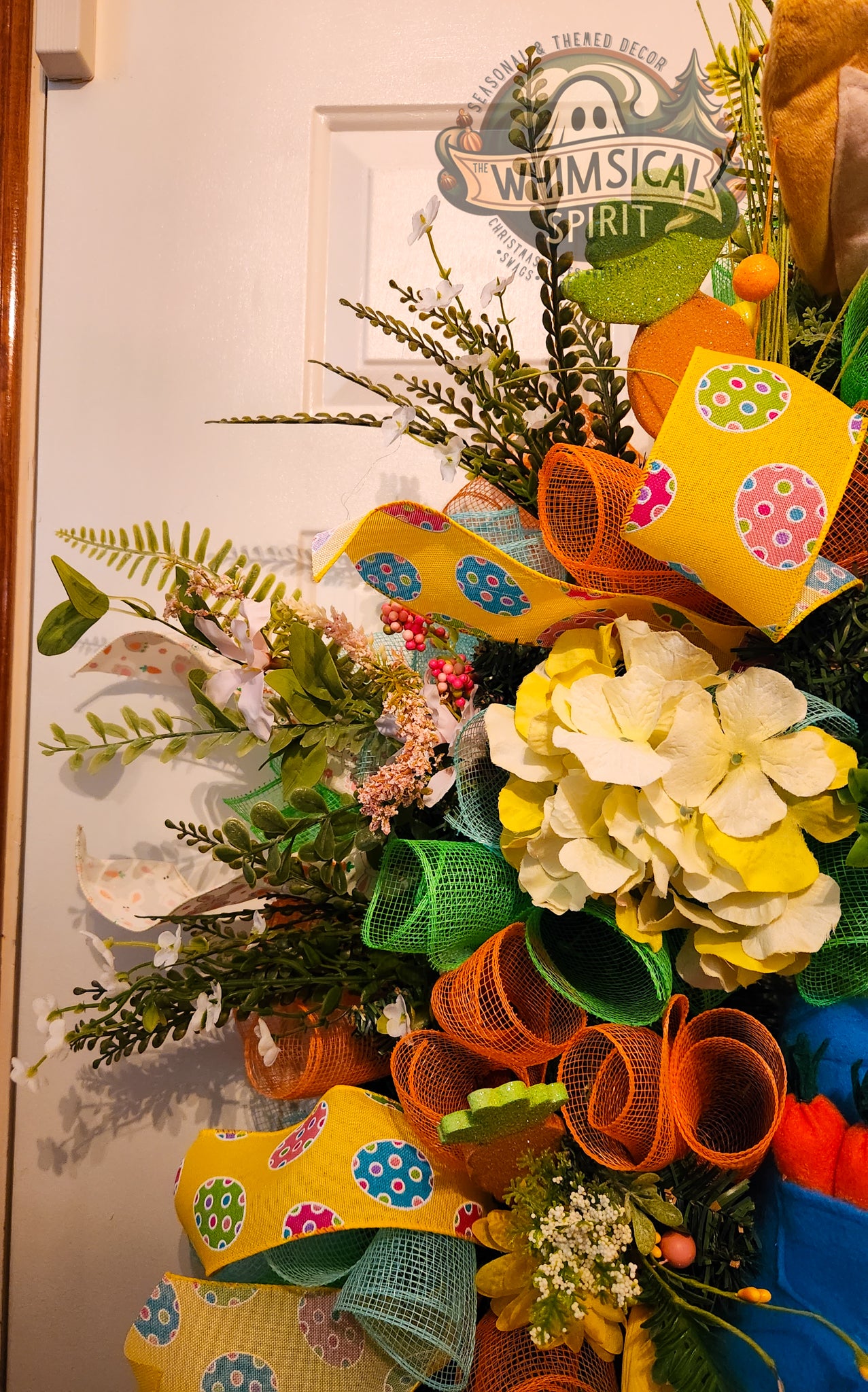 Colorful wreath with flowers and ribbons on a door