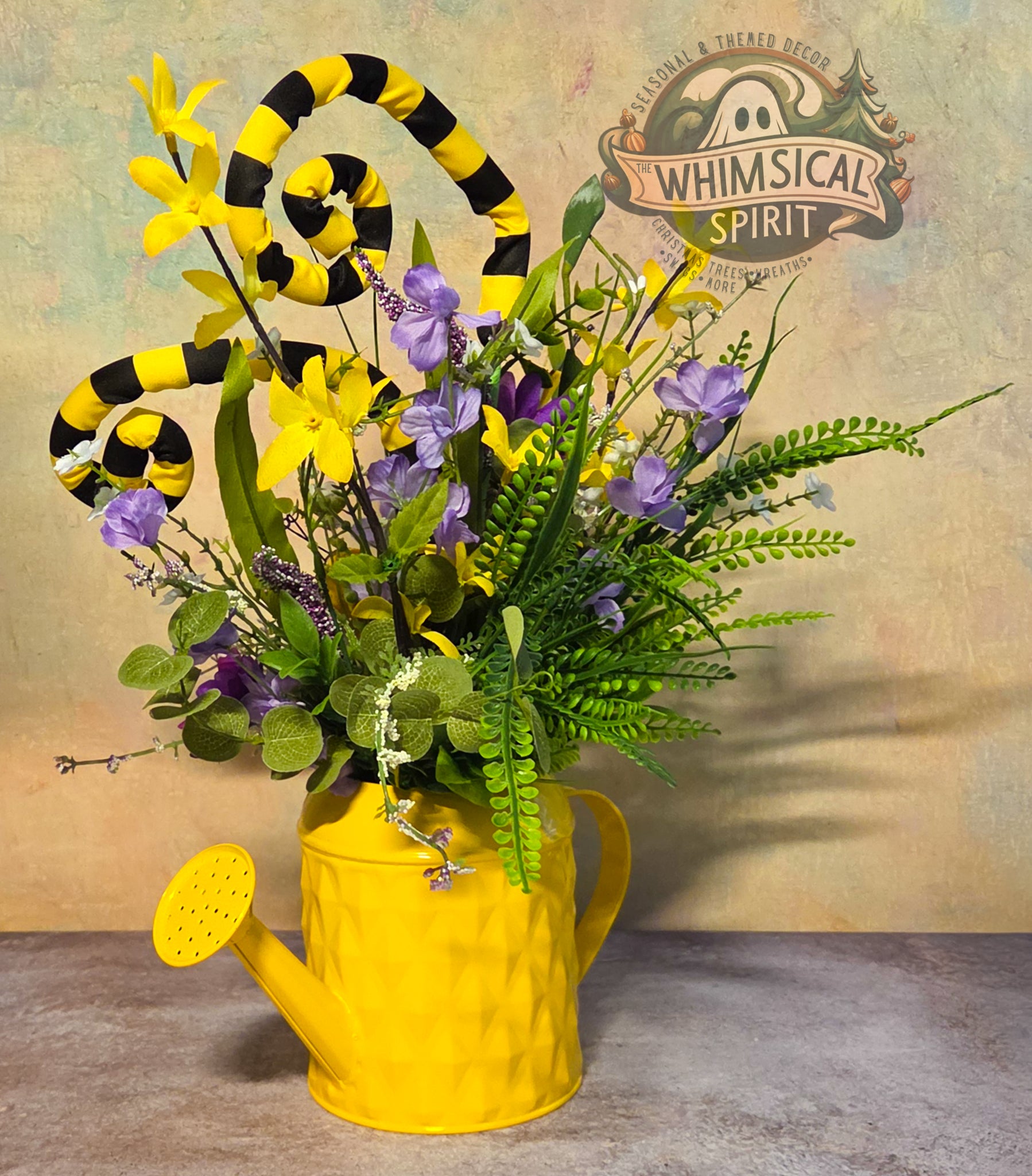 Yellow watering can with floral arrangement and candy cane decorations on a textured background with 'Whimsical Spirit' branding.