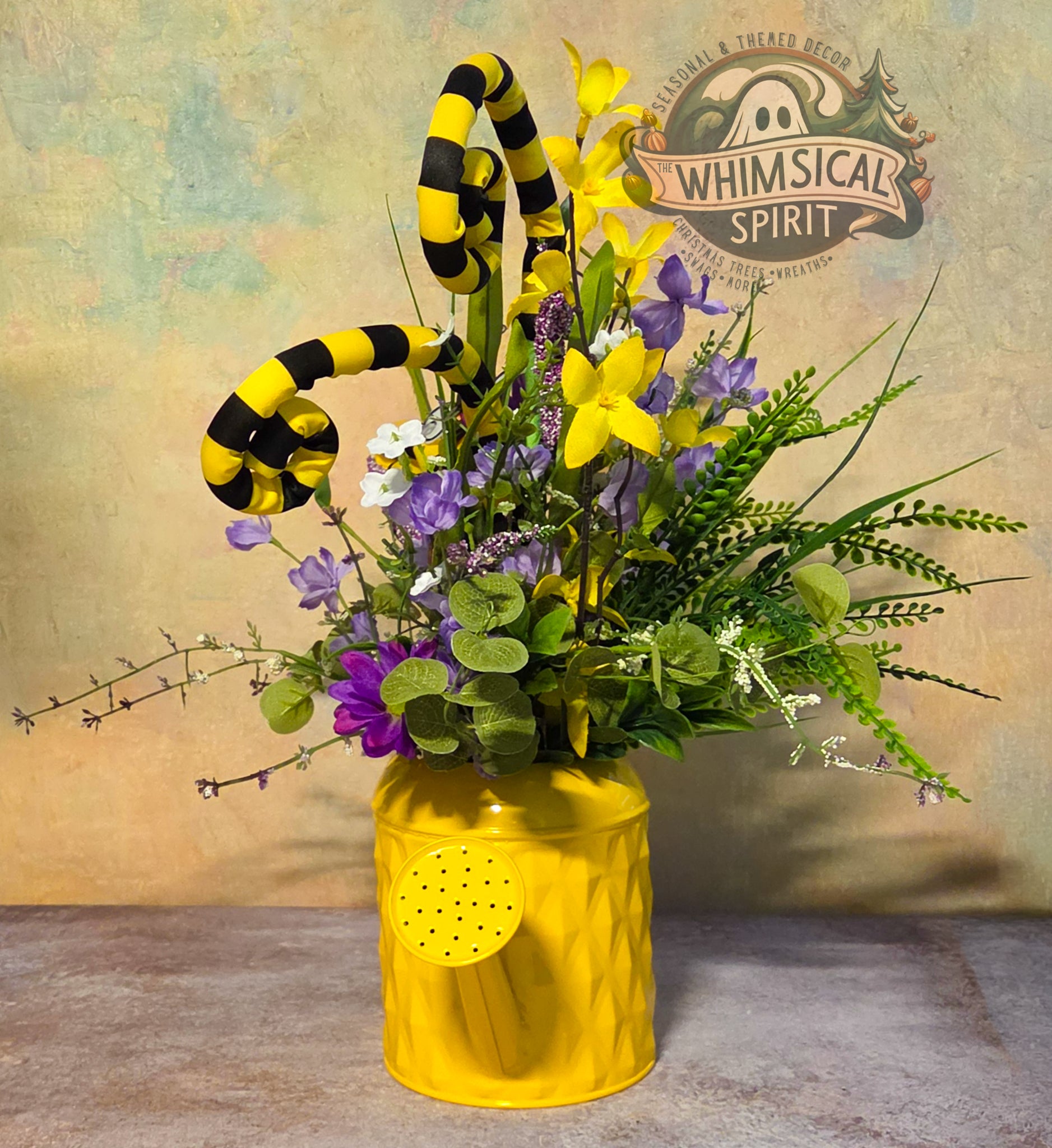 Decorative flower arrangement with yellow and black striped elements in a yellow vase, against a textured wall with 'Whimsical Spirit' branding.