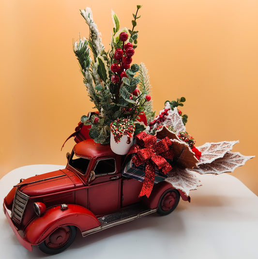 Decorative red truck with Christmas tree and decorations on a white surface and beige background