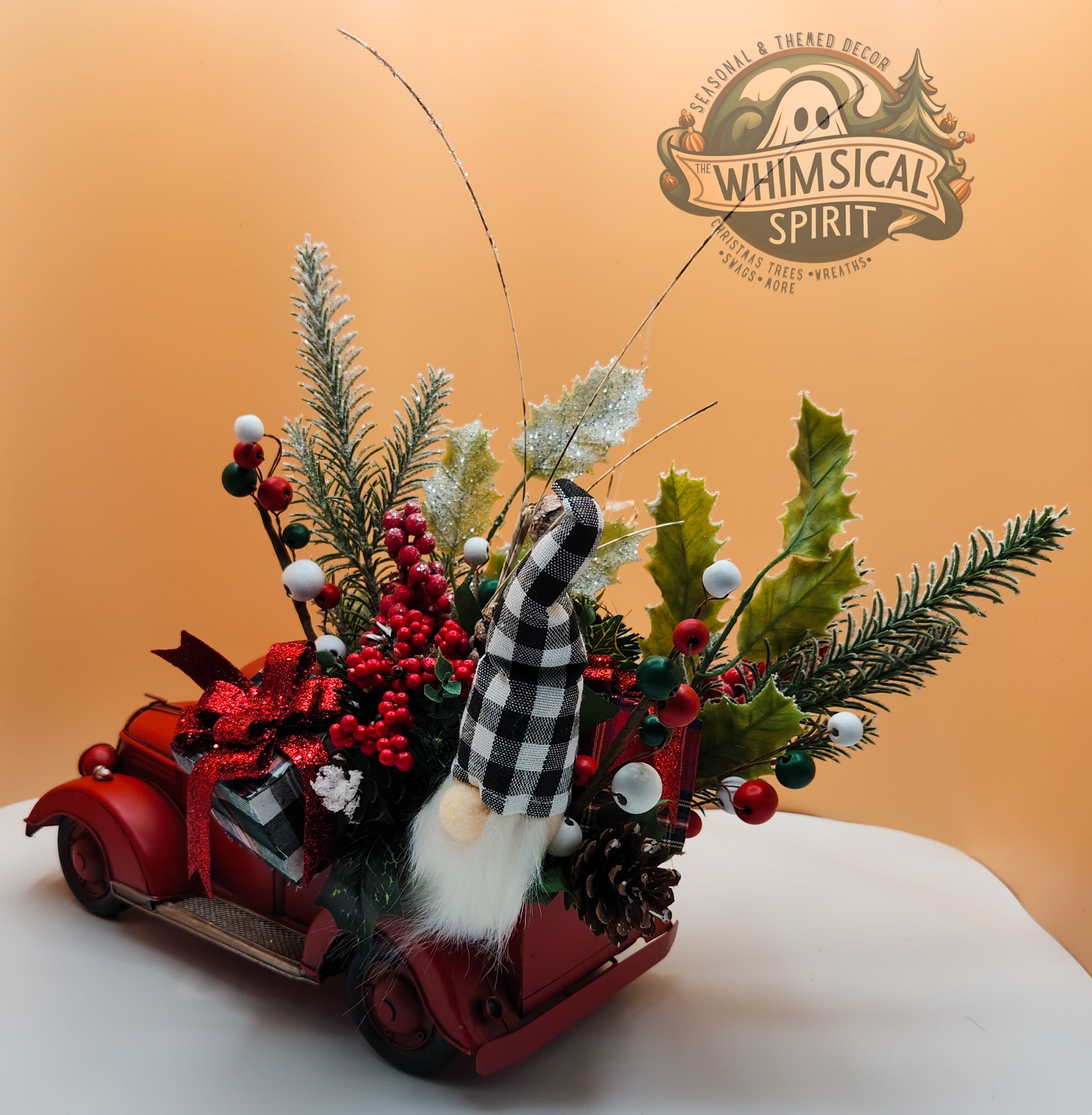 Christmas decorative display with red car, checkered gnome, festive greenery on orange background, The Whimsical Spirit branding