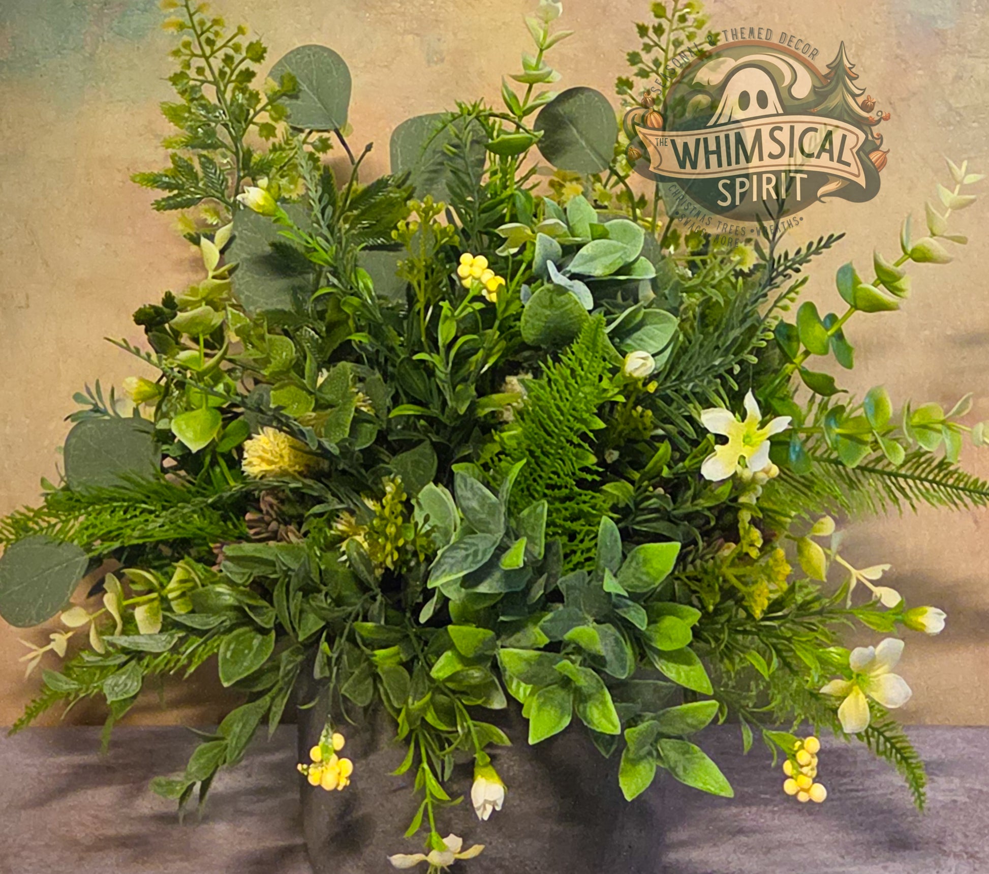 Artificial greenery arrangement with yellow flowers on a textured background, featuring 'Whimsical Spirit' branding.