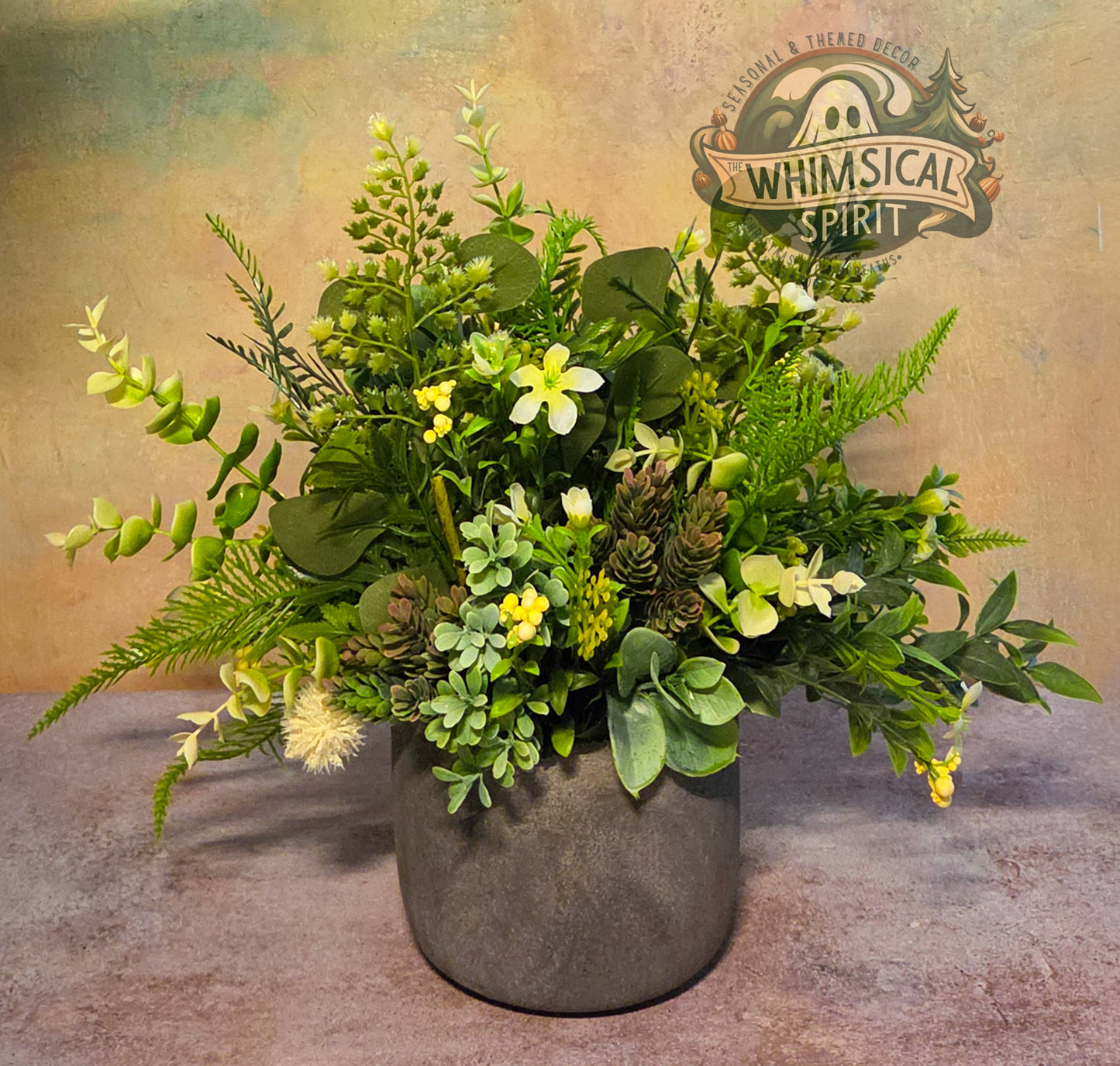 Artificial plant arrangement in a pot with 'Whimsical Spirit' logo in the background