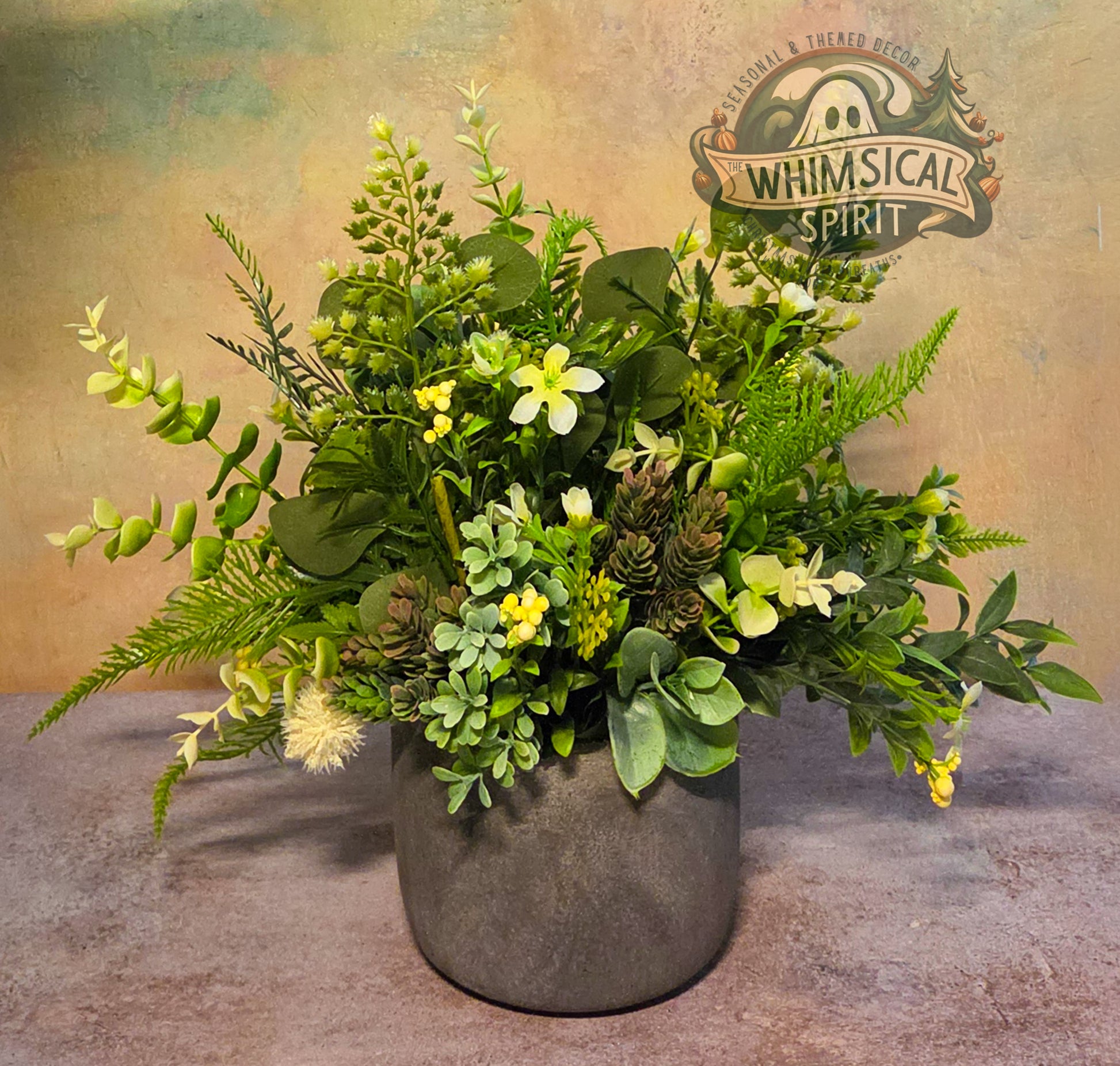 Artificial plant arrangement in a pot with 'Whimsical Spirit' logo in the background