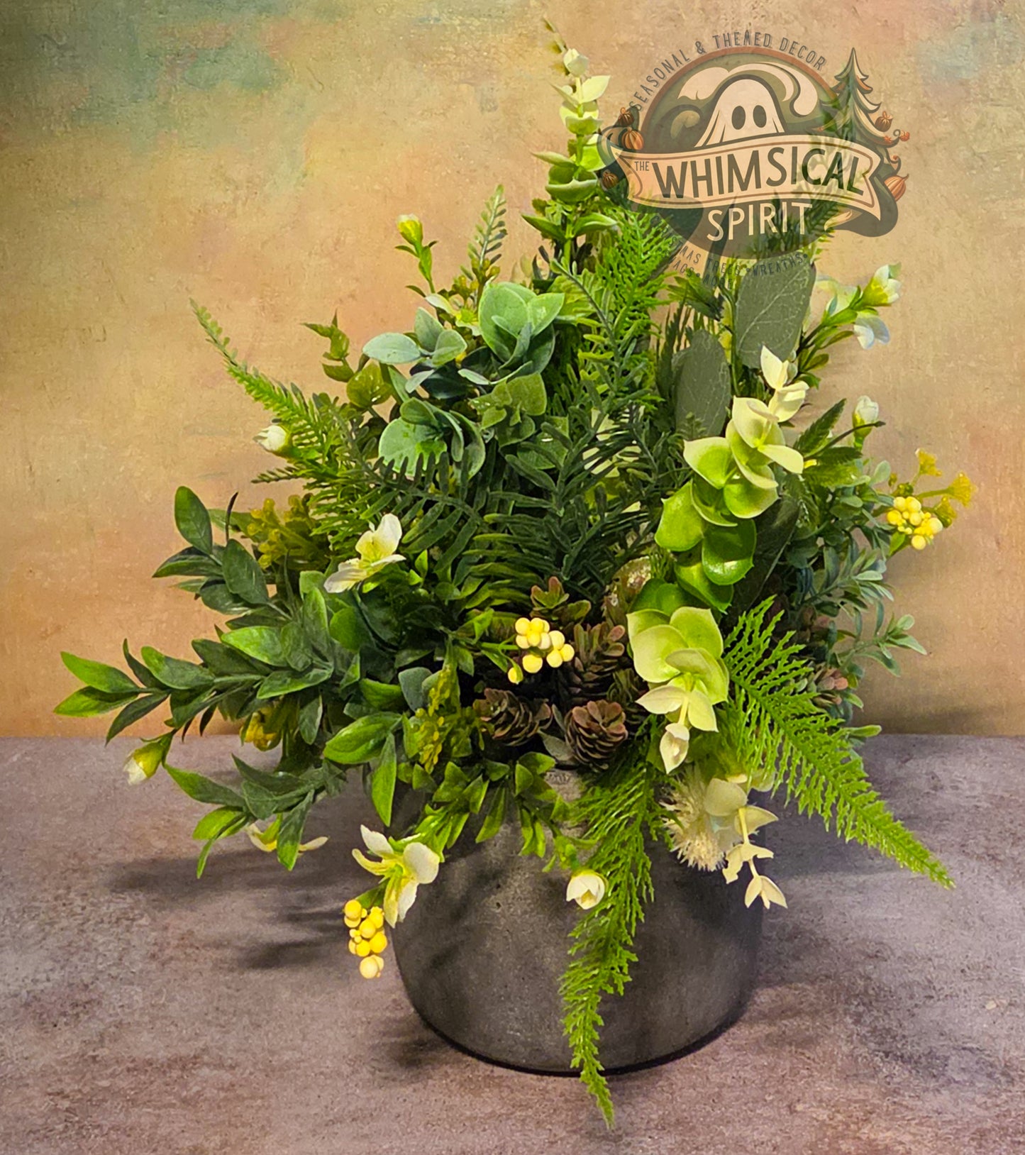 Artificial greenery arrangement in a pot with 'Whimsical Spirit' branding in the background.