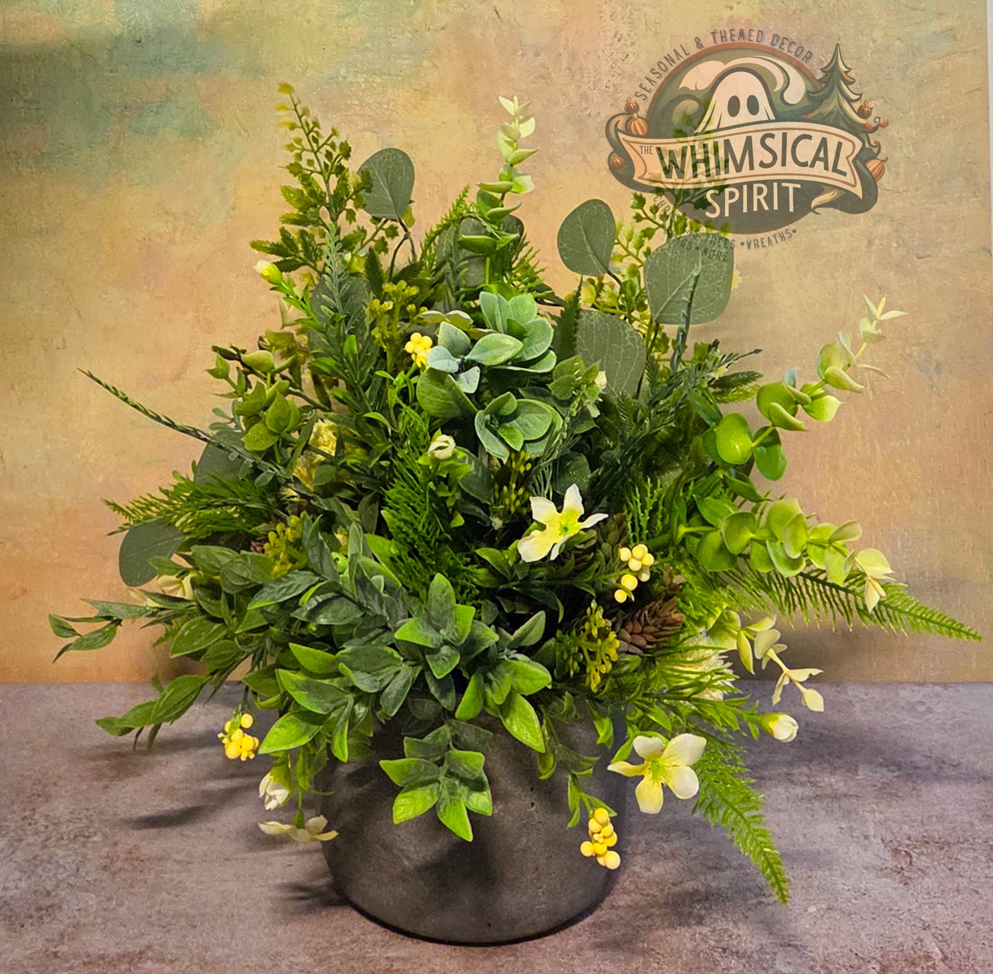 Artificial plant arrangement in a pot with 'Whimsical Spirit' logo in the background
