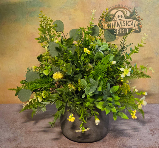 Faux greenery arrangement in a pot with 'Whimsical Spirit' branding on a textured background