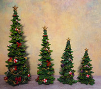 Four decorated resin Christmas tree tabletop figurines in graduated sizes with gold star toppers, red bows, candy canes, ornaments, and gold garland.