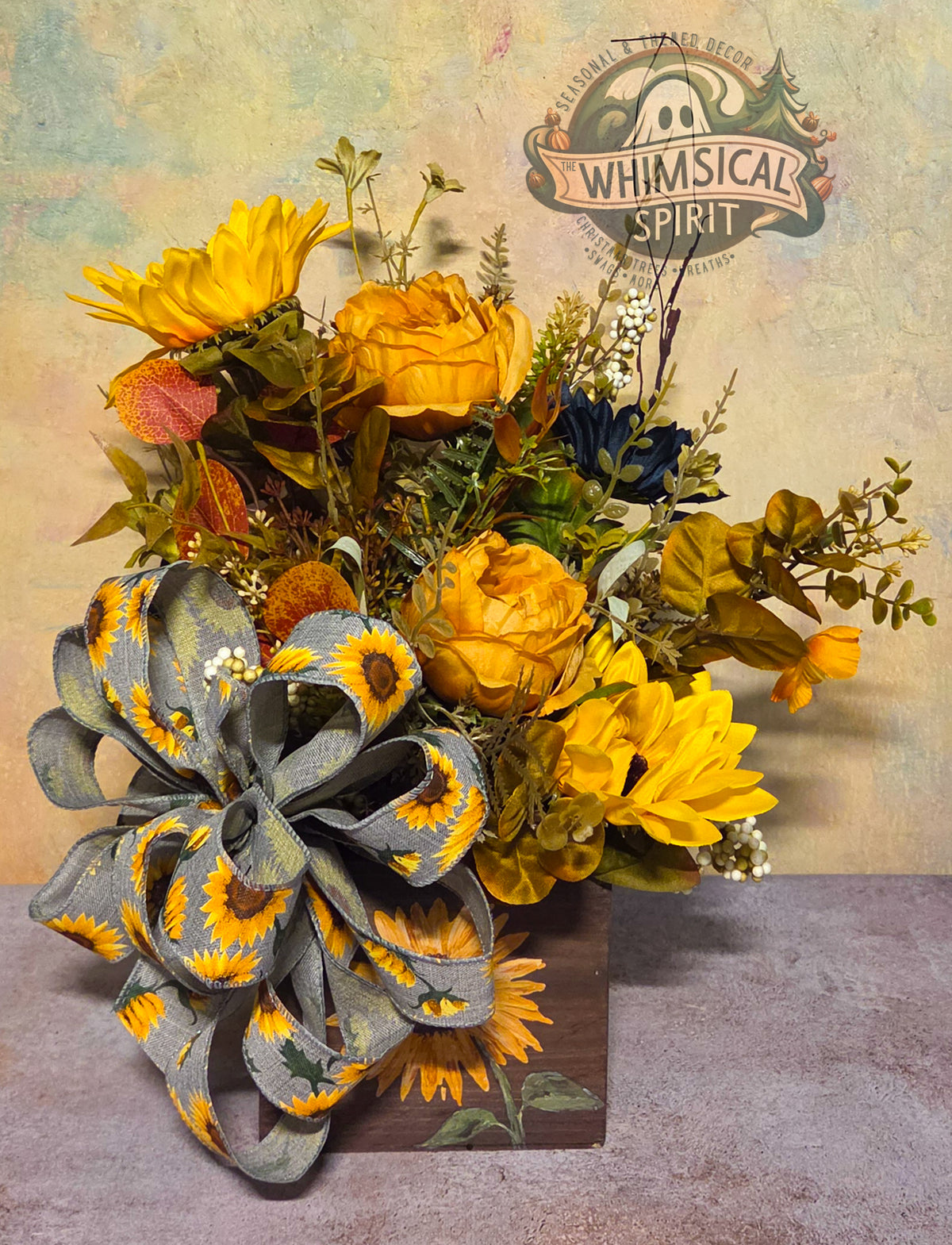 Rustic fall centerpiece with golden sunflowers, amber and navy flowers, greenery, white berries, and a large gray sunflower bow.