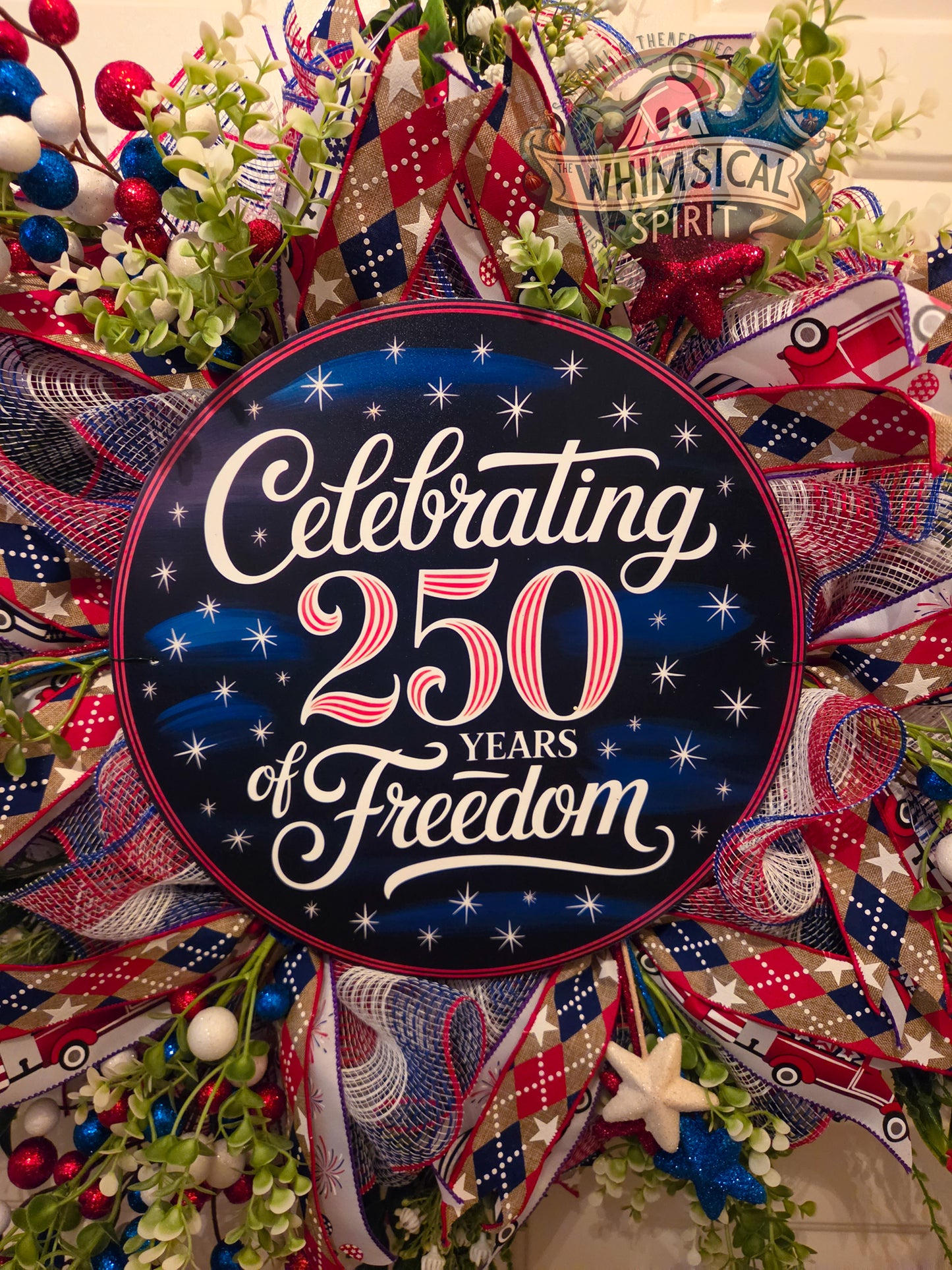 Decorative wreath with 'Celebrating 250 Years of Freedom' text and festive ribbons.