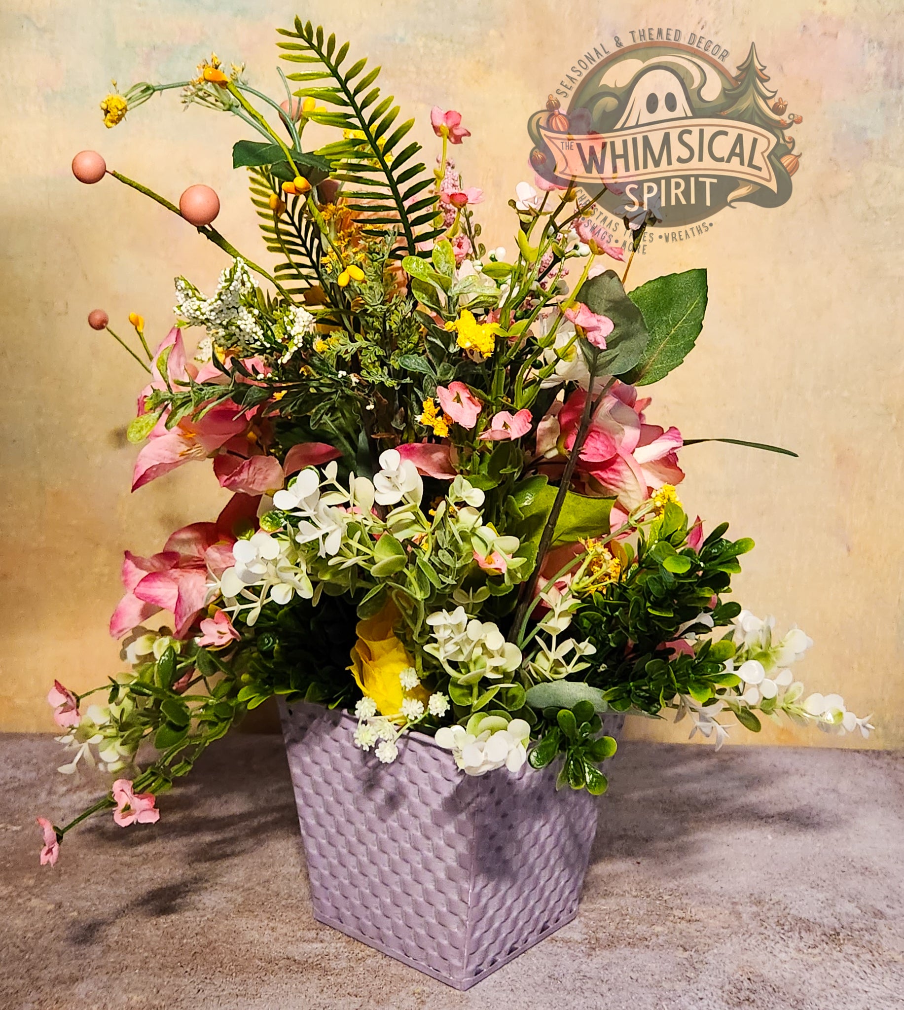 Floral arrangement in a woven basket with 'Whimsical Spirit' branding in the corner.