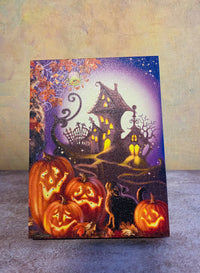 Haunted House light-up Halloween tabletop canvas featuring glowing jack-o’-lanterns, a crooked haunted house, black cat, and moonlit path.