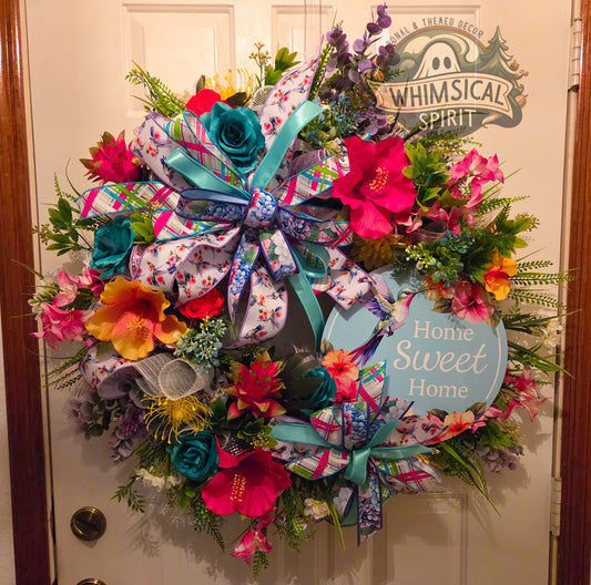 Colorful floral wreath with a 'Home Sweet Home' sign on a door, featuring the brand 'Whimsical Spirit'.