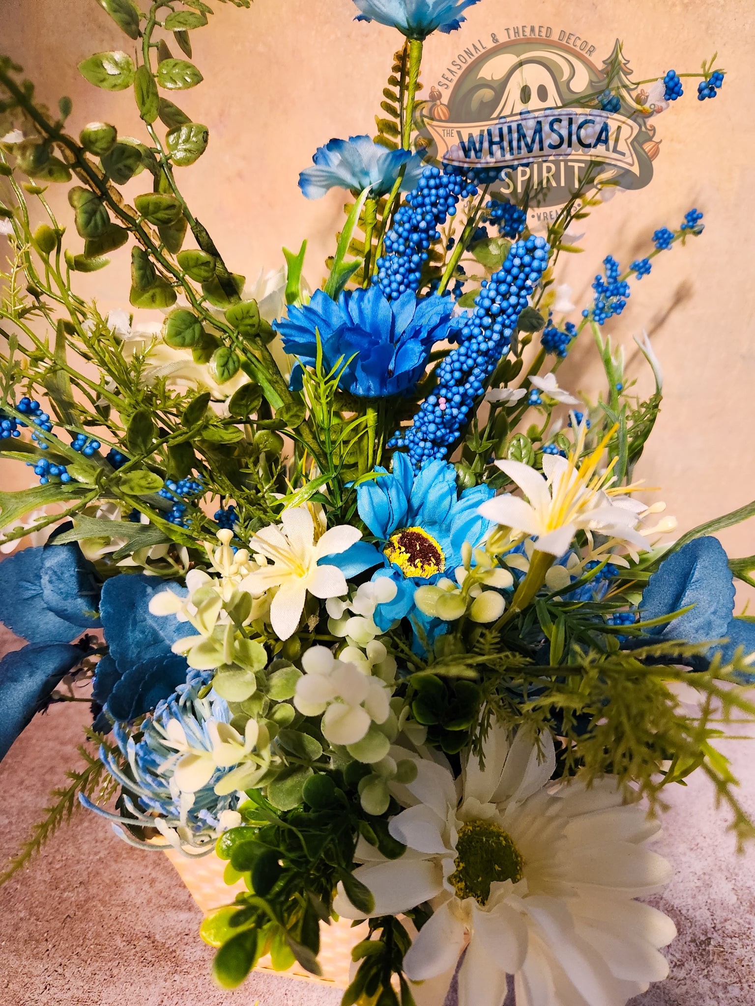 Bouquet of blue and white flowers with greenery on a beige background