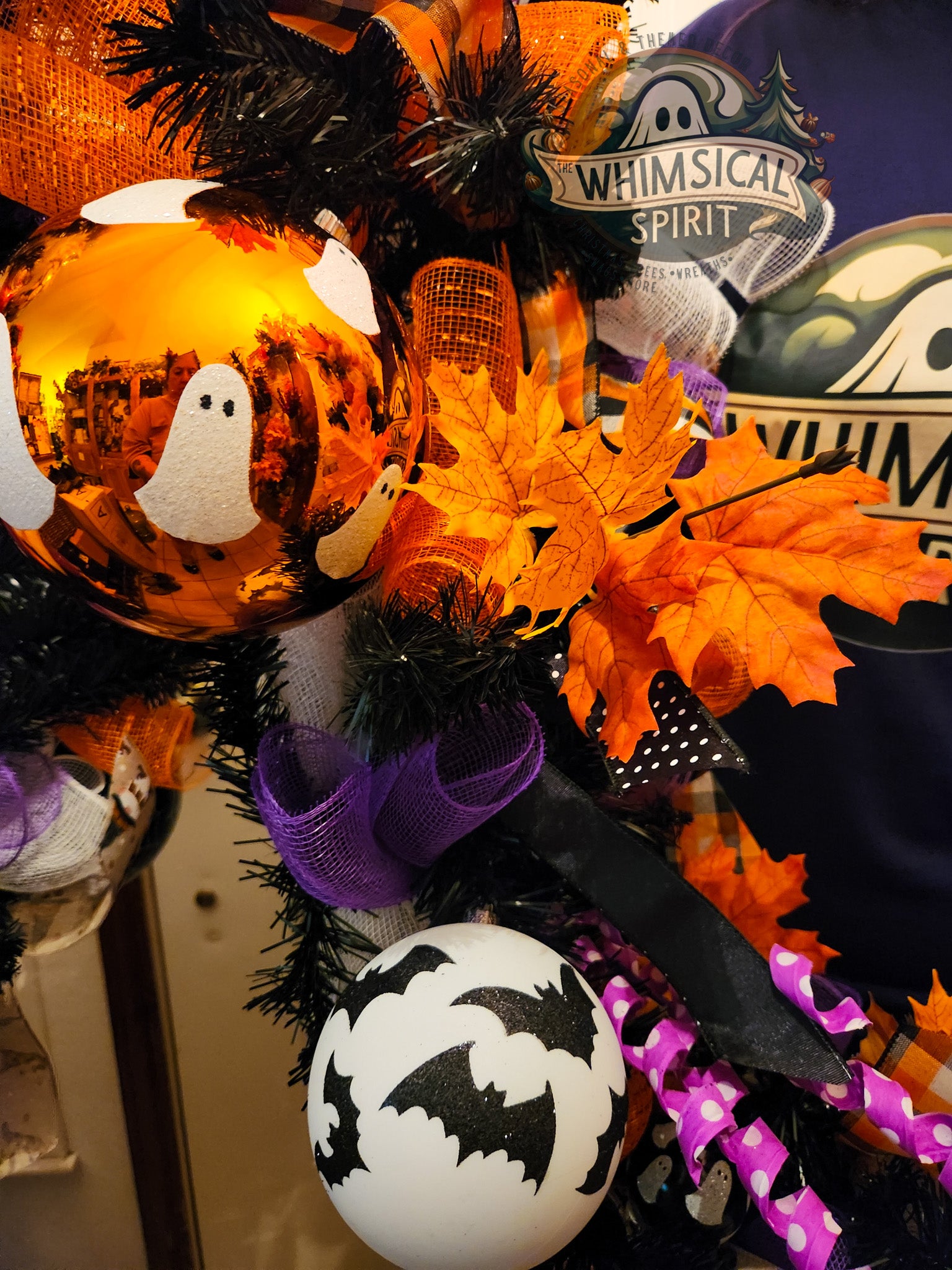 Halloween-themed wreath with pumpkins, ghosts, and bats on a door.