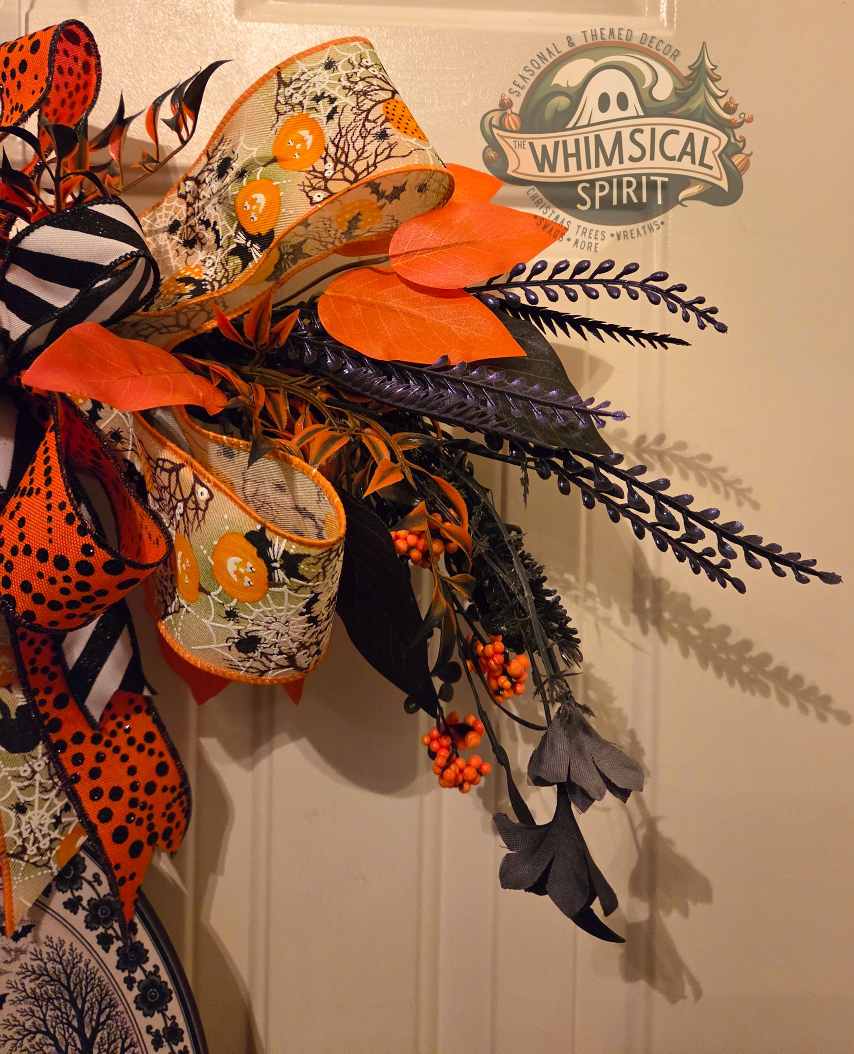 Decorative Halloween wreath with orange, black, and white elements on a plain background.