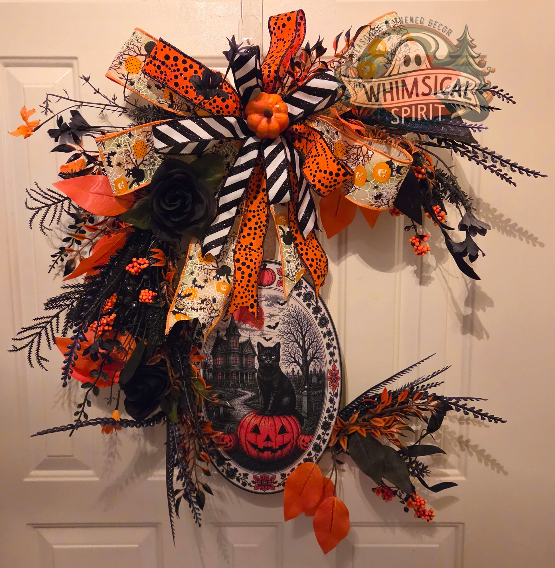 Halloween-themed decorative bow with pumpkins, ghosts, and other festive elements on a white door.